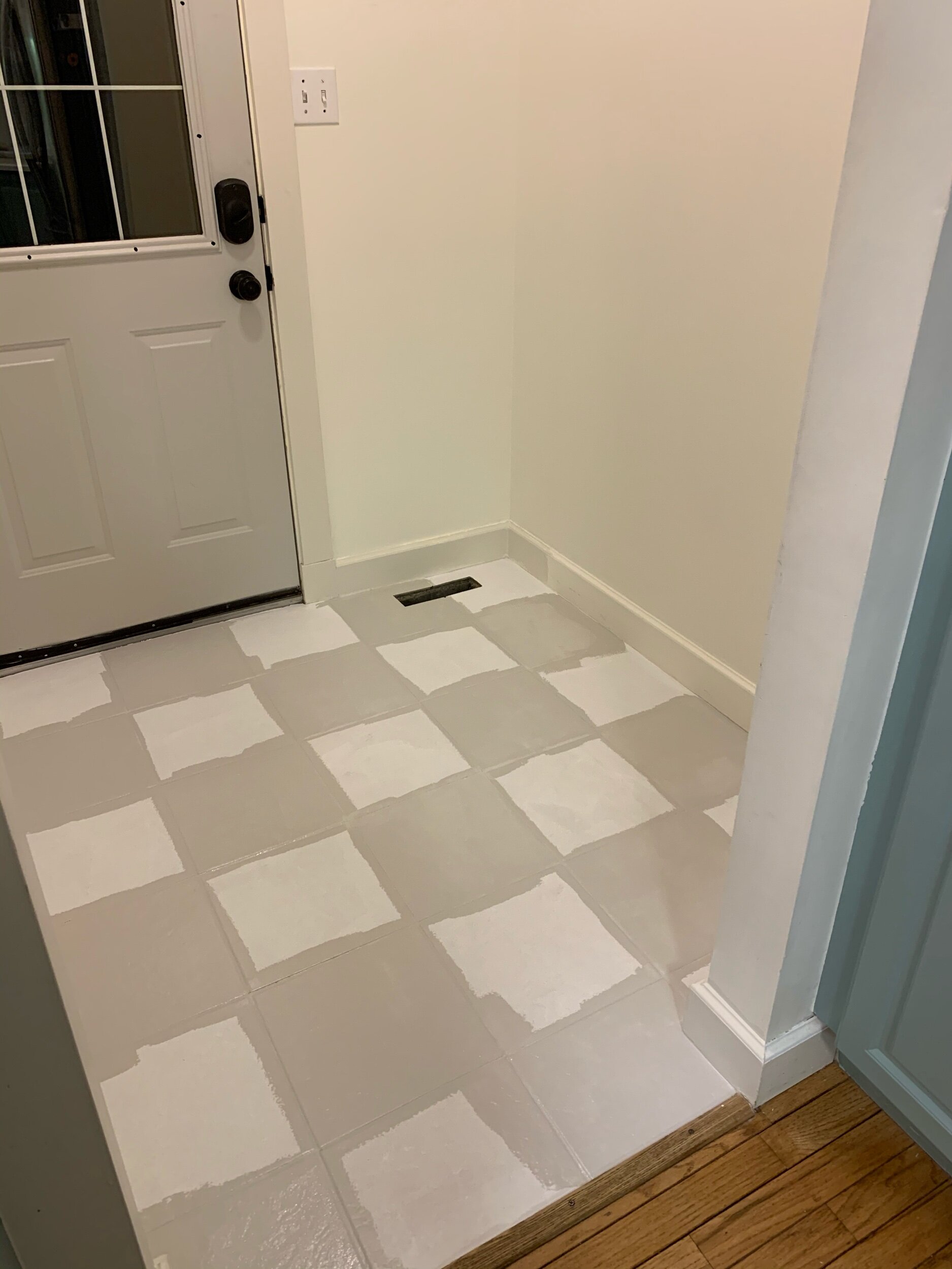 this is a photo of the beginning stages of painting tile floors in a checkerboard patter using repose grey by sherwin williams paint