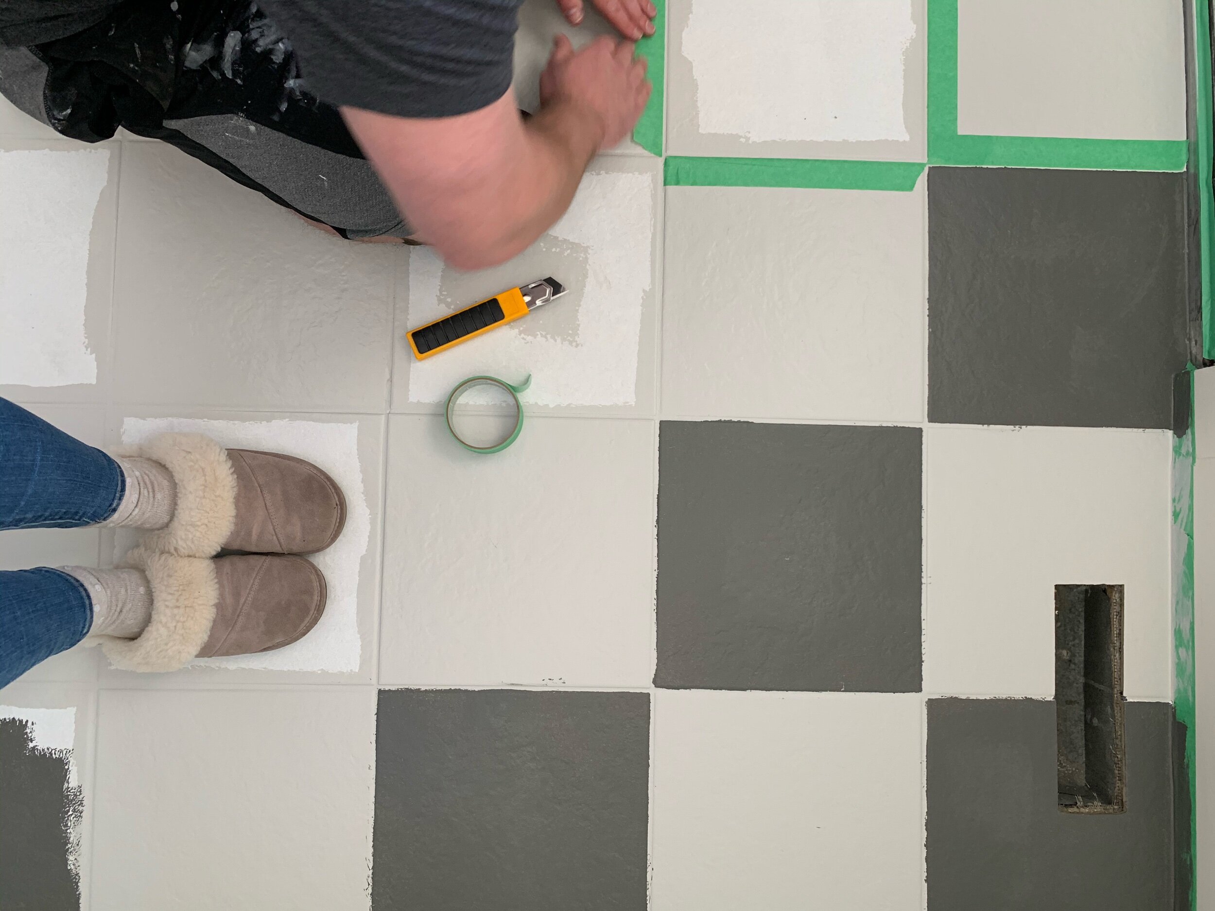 this is a photo of creating a checker board pattern with frog tape on tile floors with repose grey paint and kendall charcoal paint