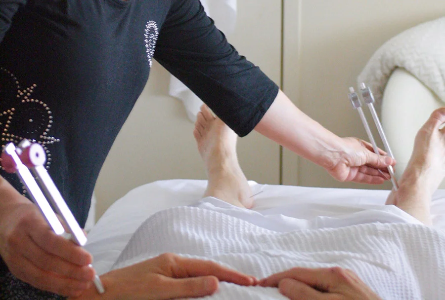 Acupuncturist using tuning fork therapy on patient