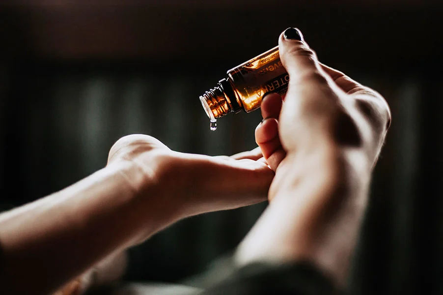 Acu raindrop essential oils dripping from bottle onto hand