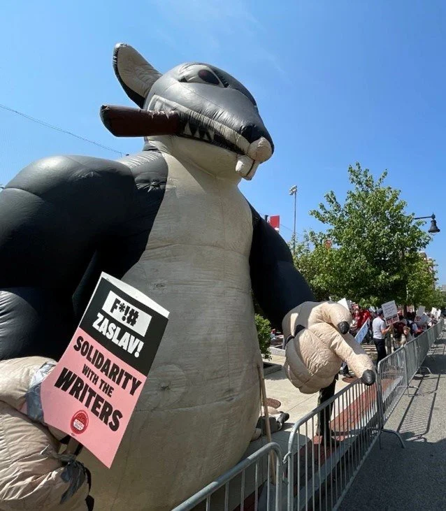 A "Scabby" holding a picket sign that reads: "F*!# Zaslav! Solidarity with the Writers."
