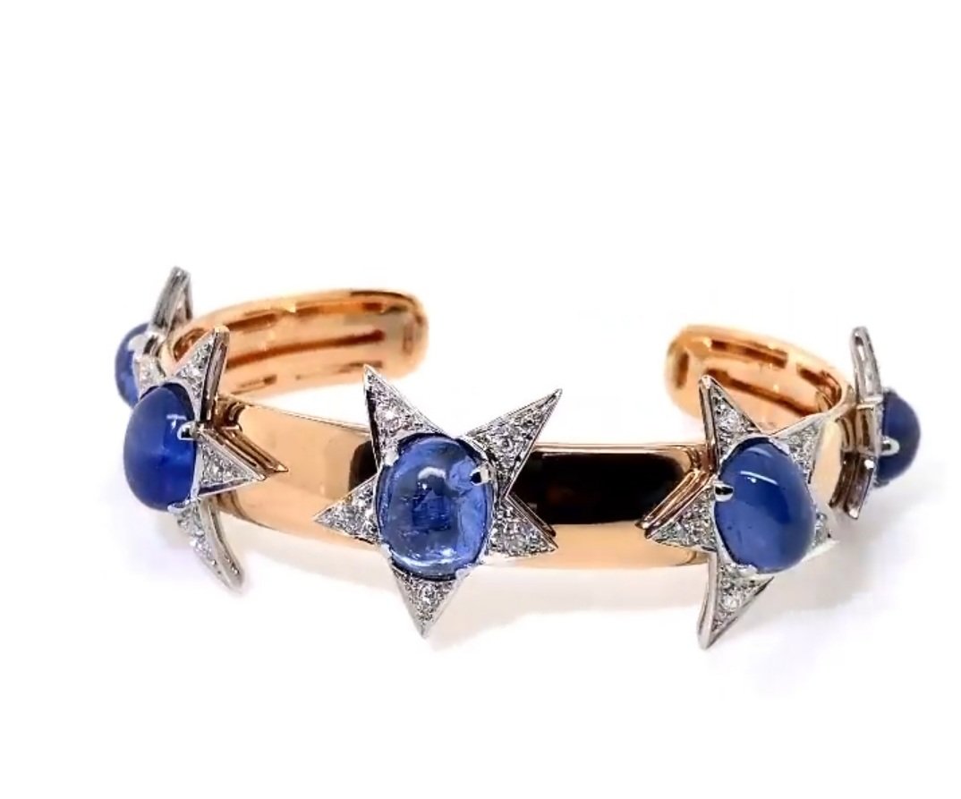 SAPPHIRE AND DIAMOND, PLATINUM AND GOLD  STAR BANGLE BRACELET. The five star elements from a 1960's piece, set wiith 5 cabochon sapphires 28  cts, OEC dias 2.5 cts in  platinum, now set in a later added 18kt rose gold 18.2 grams bangle bracelet. With