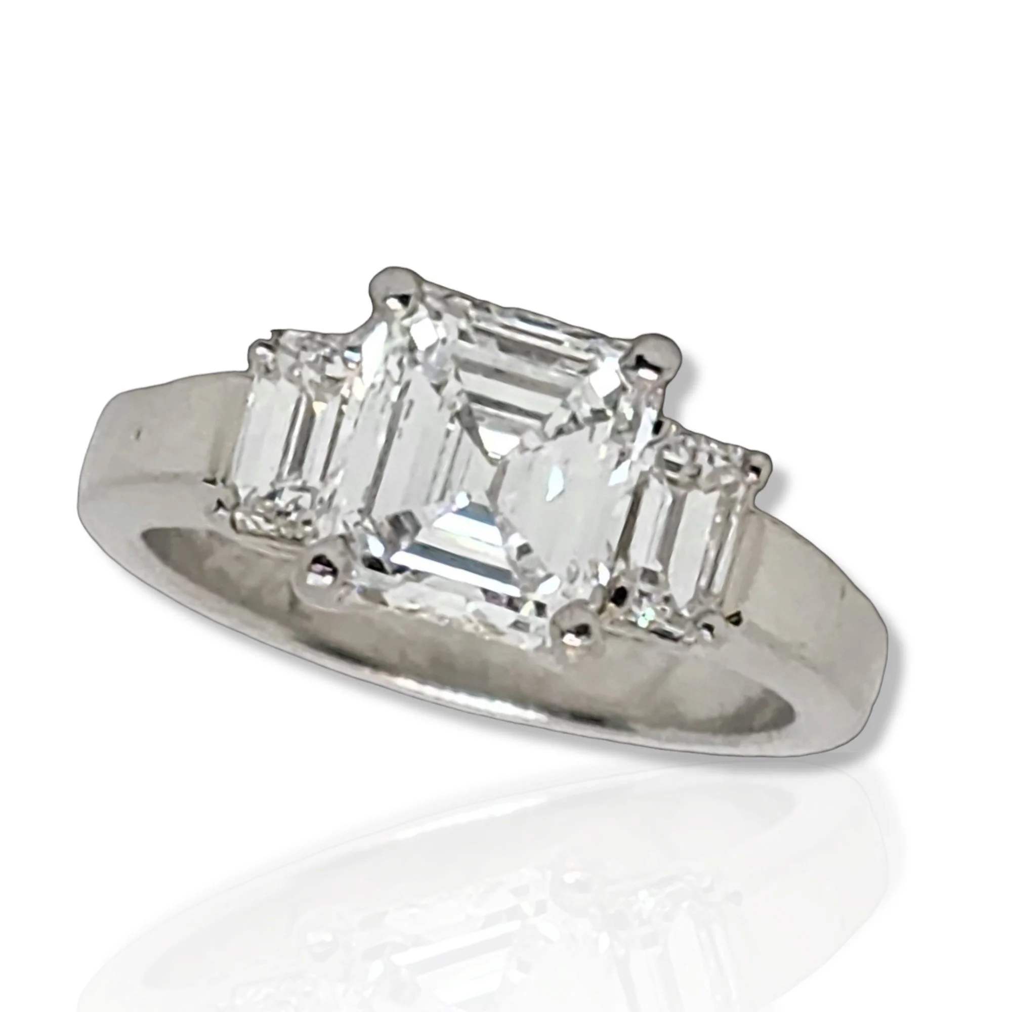 PLATINUM AND DIAMOND THREE STONE RING Centering upon an emerald cut diamond weighing 2.11 cts GIA G/VS2 prong set and flanked by a pair of emerald cut diamonds weighing approximately 0.60 cts to the platinum ring with GIA report 6223659917 dated 29 S
