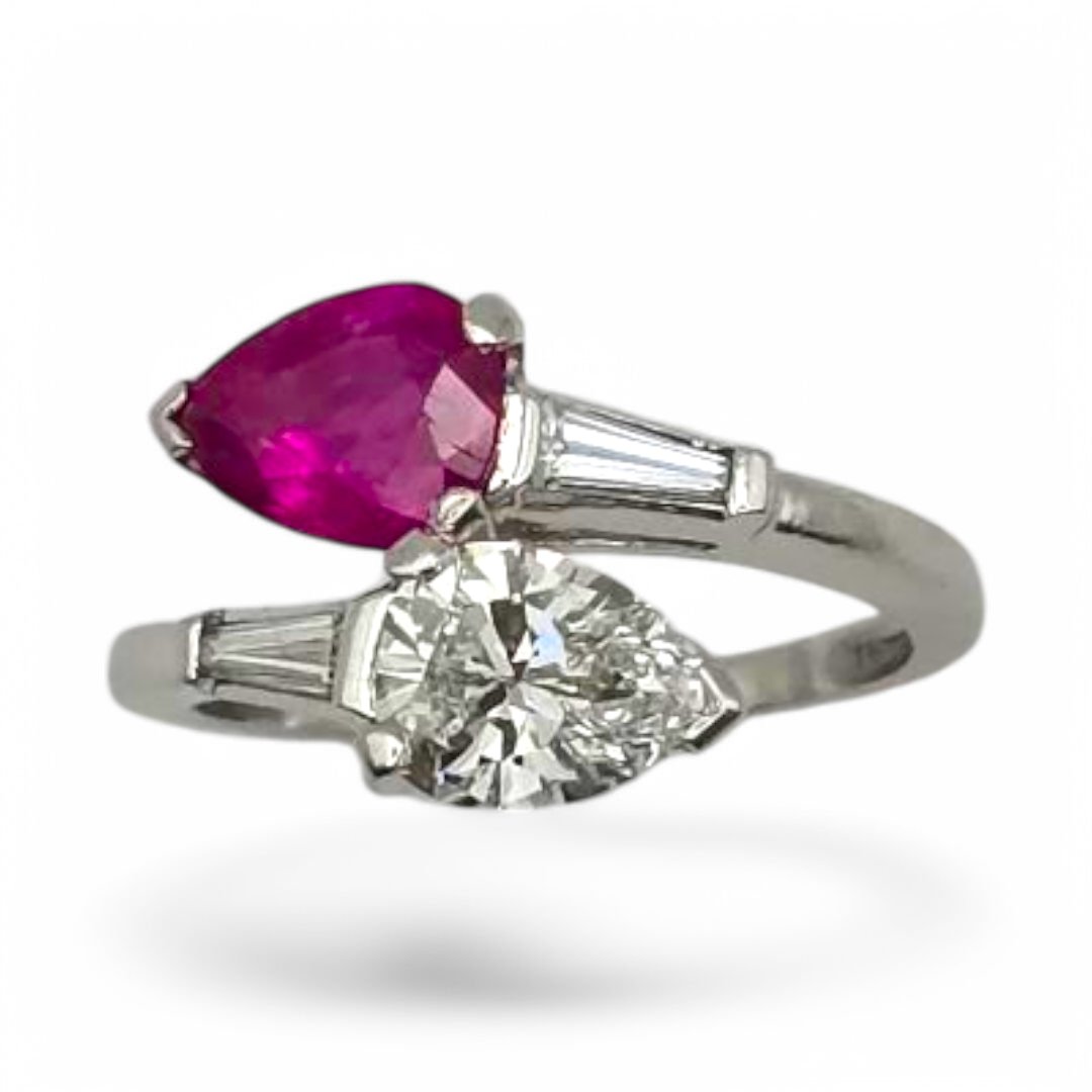 1950's PLATINUM, RUBY AND DIAMOND TWIN RING. Pear shaped diammond 0.87 cts and Pear shaped Burma ruby 1.14 cts flanked by a pair of tapered baguette diamonds