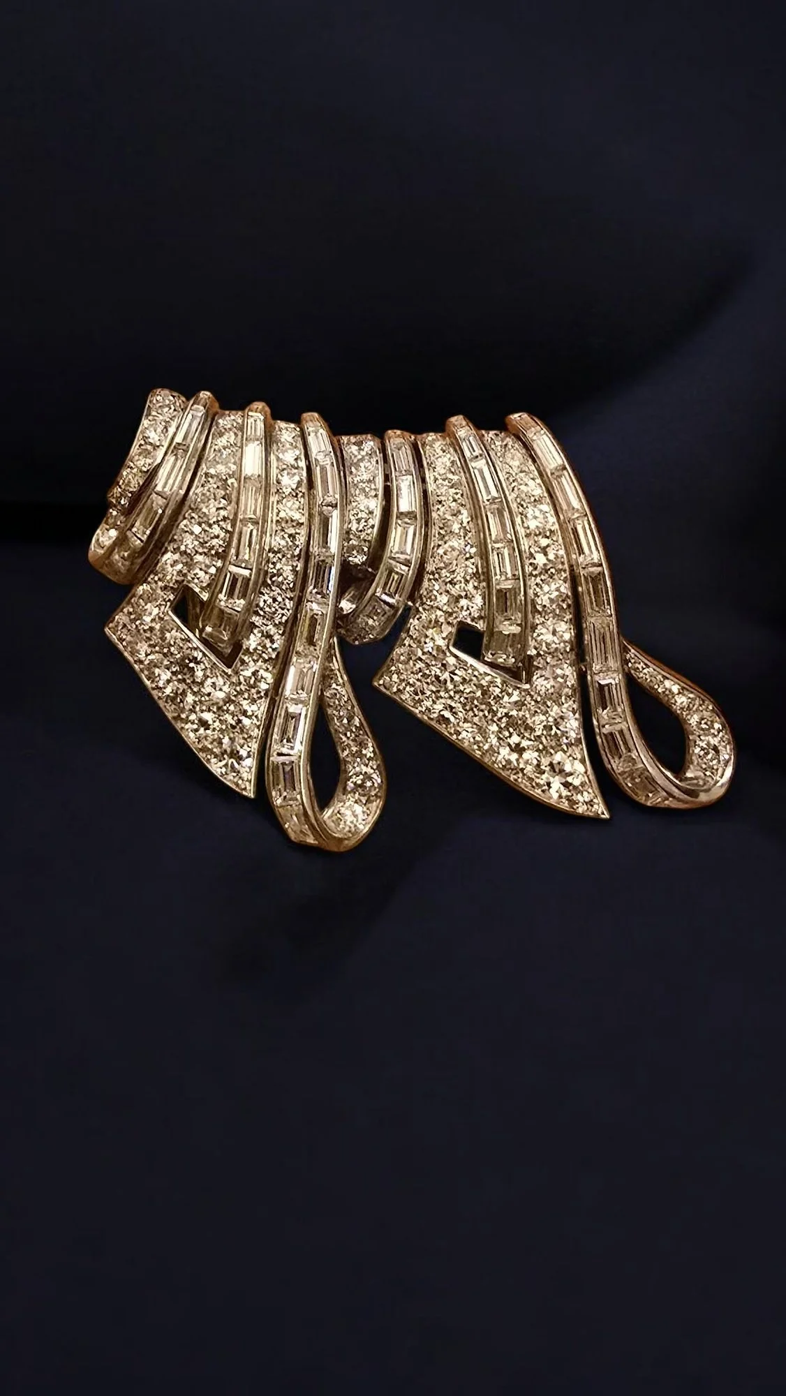 VAN CLEEF & ARPELS PLATINUM AND DIAMOND DOUBLE CLIP BROOCH. 
Two platinum clips of ribbon design set with circa 12 cts of baguette and brilliant cut diamonds. Signed Van Cleef & Arpels and numbered 50052, with maker's mark and French Hallmarks.