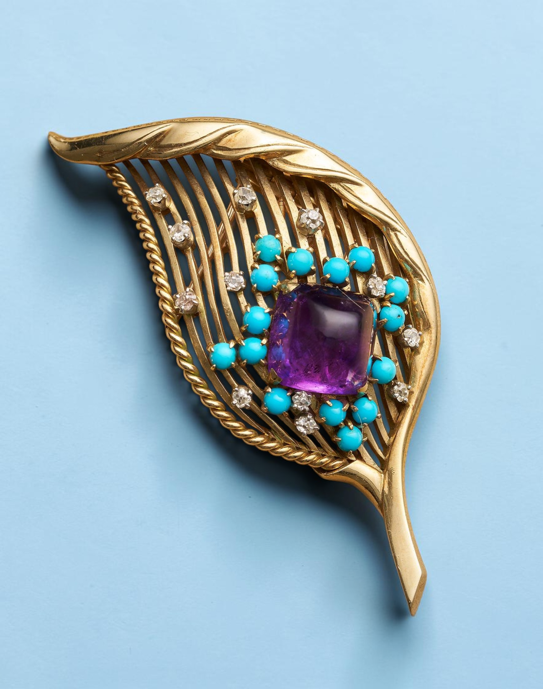 CARTIER MID CENTURY AMETHYST, TURQUOISE AND DIAMOND GOLD BROOCH
The sugarloaf amethyst surrounded by turquoise cabochons and rose-cut diamonds to an open wire-work yellow gold leaf mount, signed Cartier London, number 4668, accompanied by maker's box