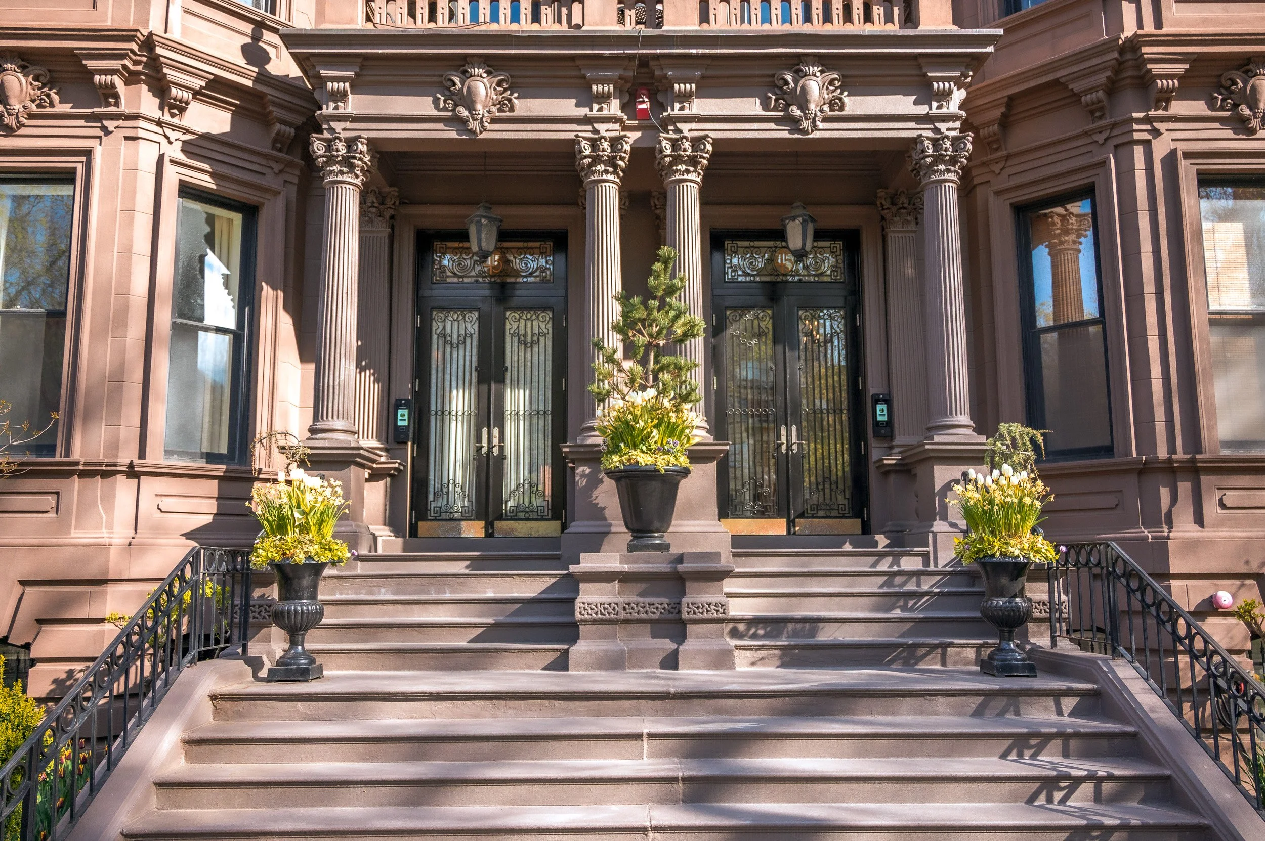 Carved Corinthian columns and daffodil urns on a Back Bay stairway, Boston, in strong afternoon spring light 