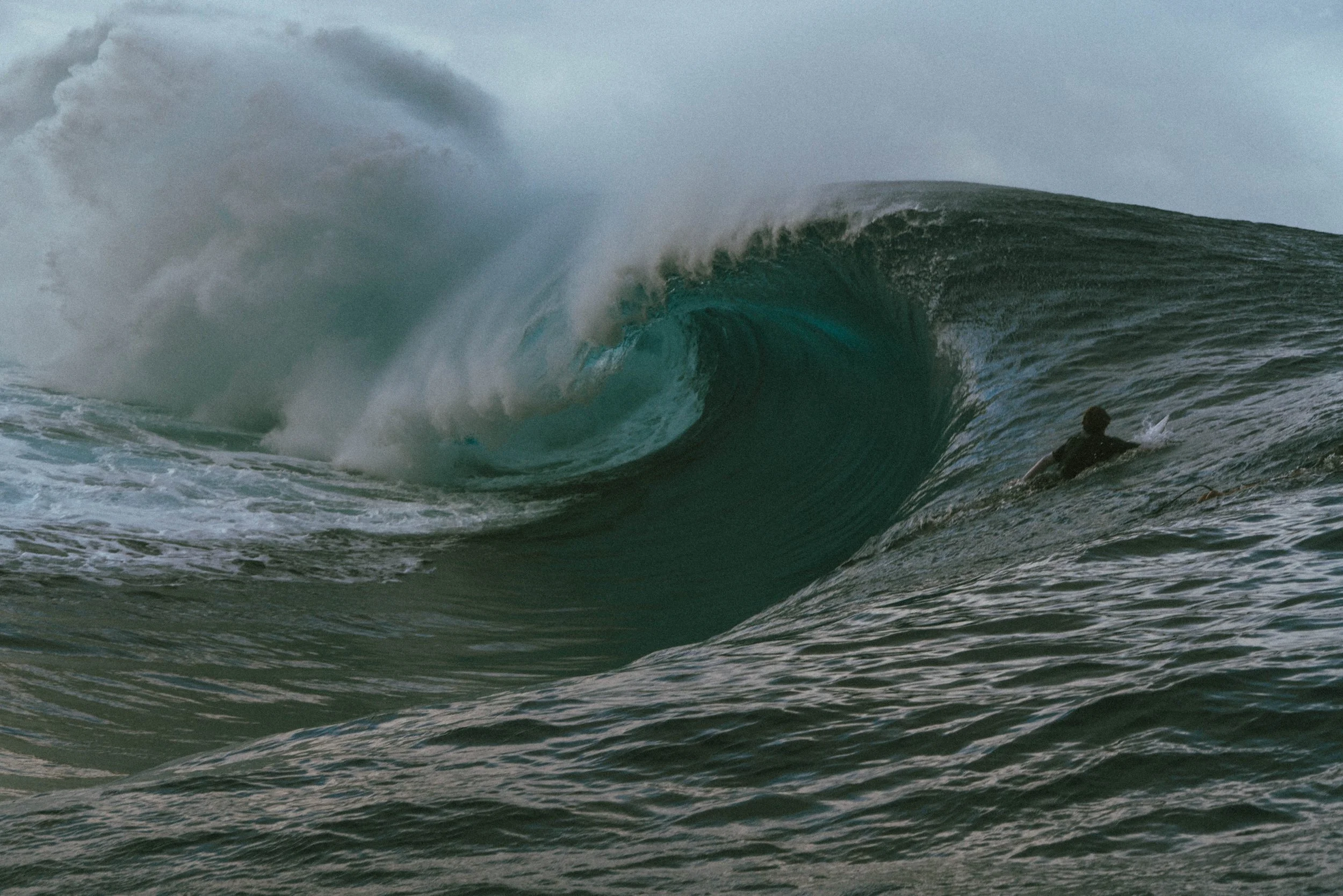 A person surfing on a large ocean wave during daytime.
