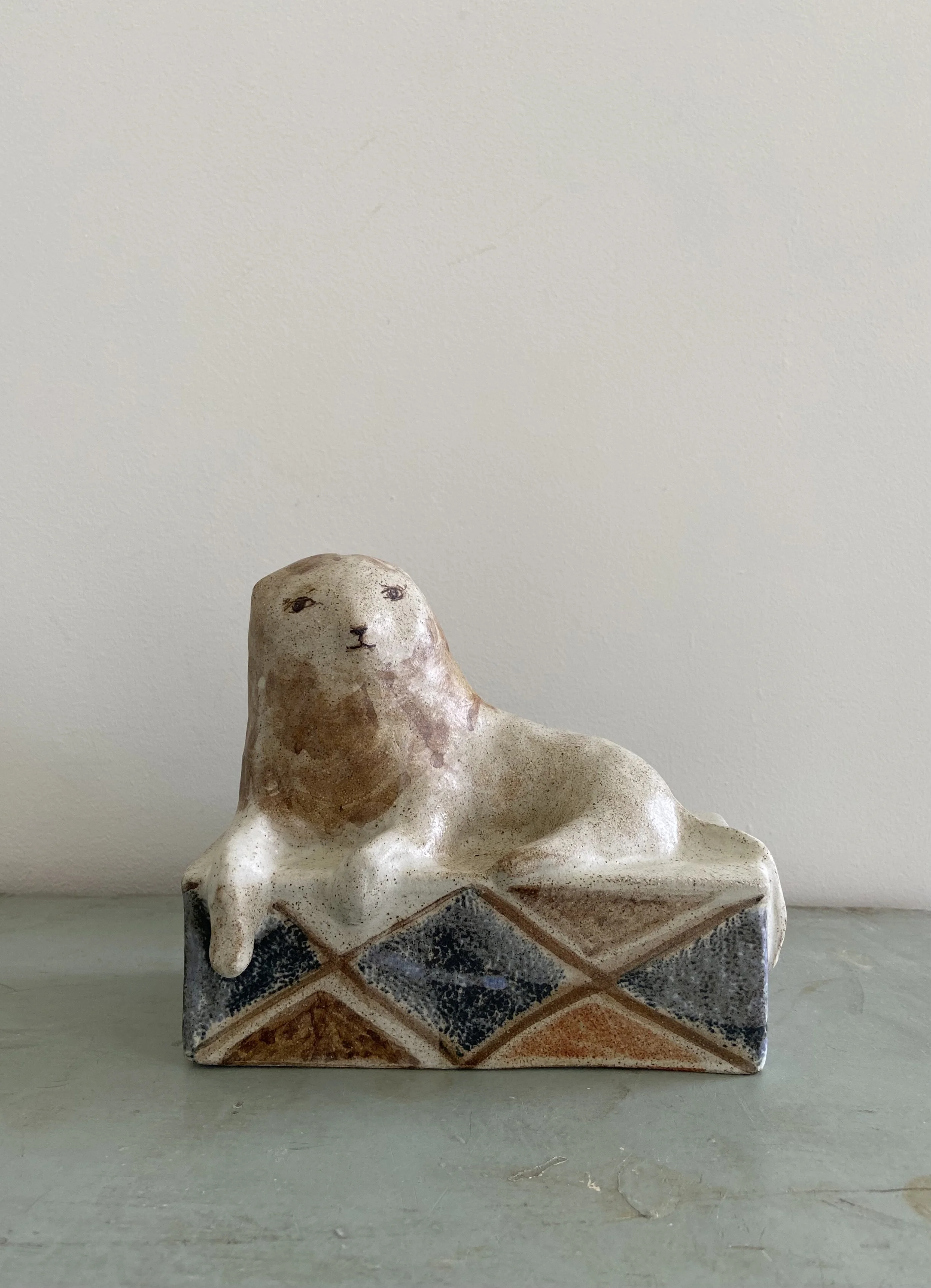 Resting Lion on a Diamond Pattern Plinth