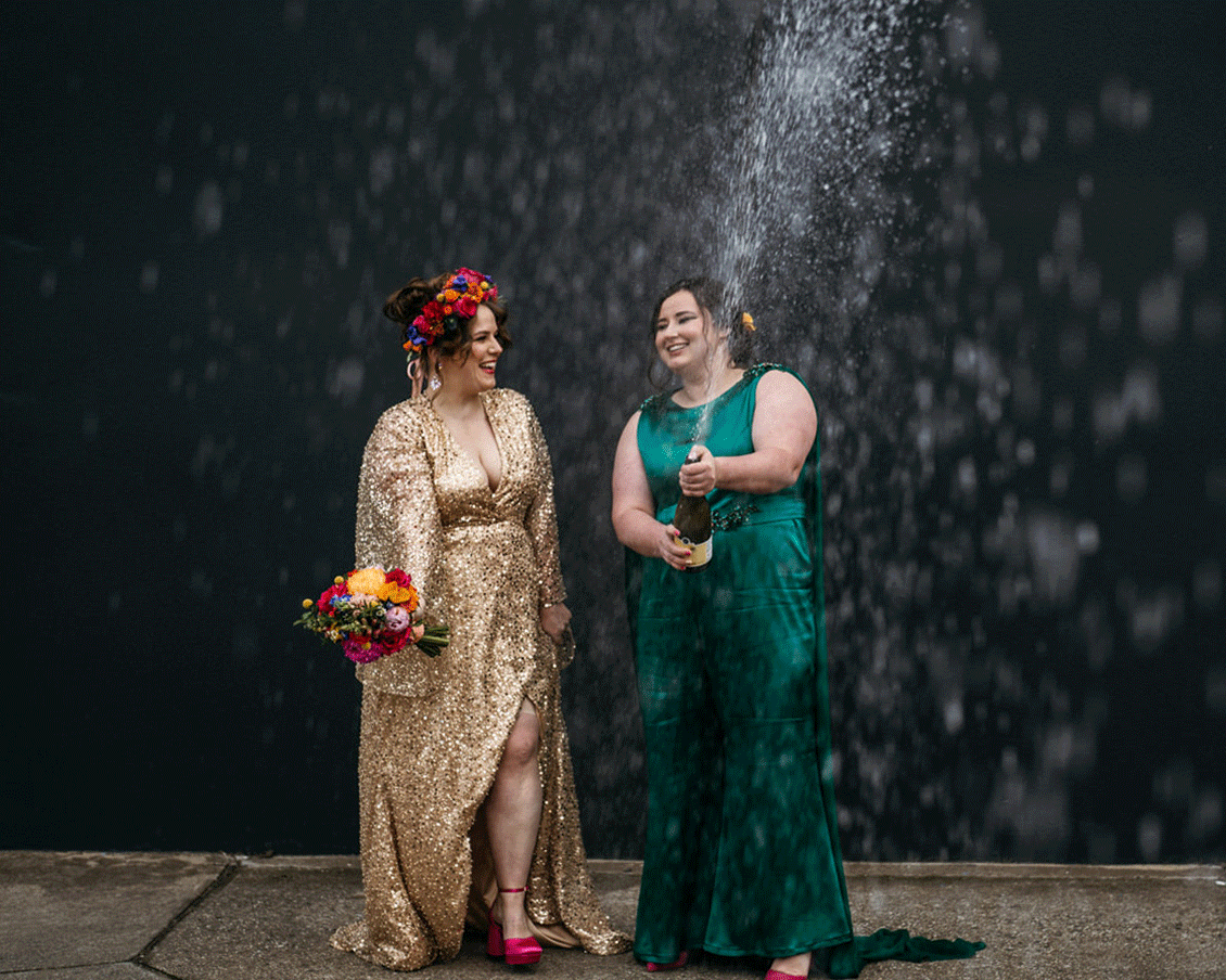 Two brides spraying a bottle of champagne in Melbourne Laneway wedding