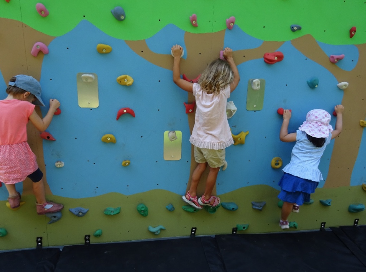 Young Children bouldering on the Climbing Wall in the Garden