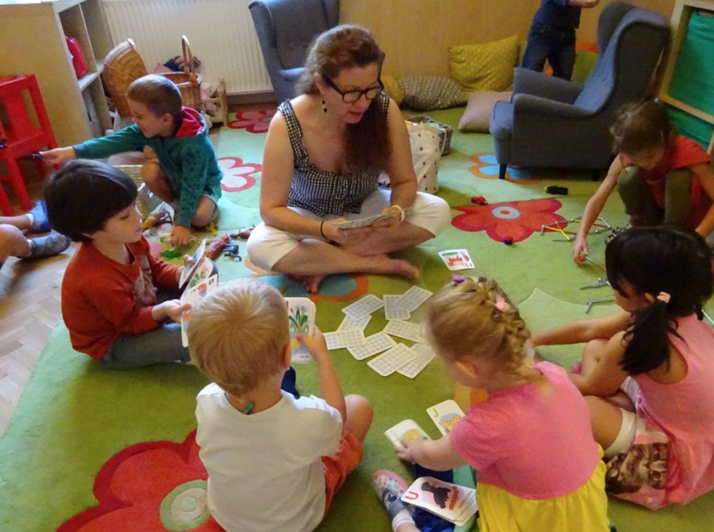 Children Playing Cards with Teacher on Carpet