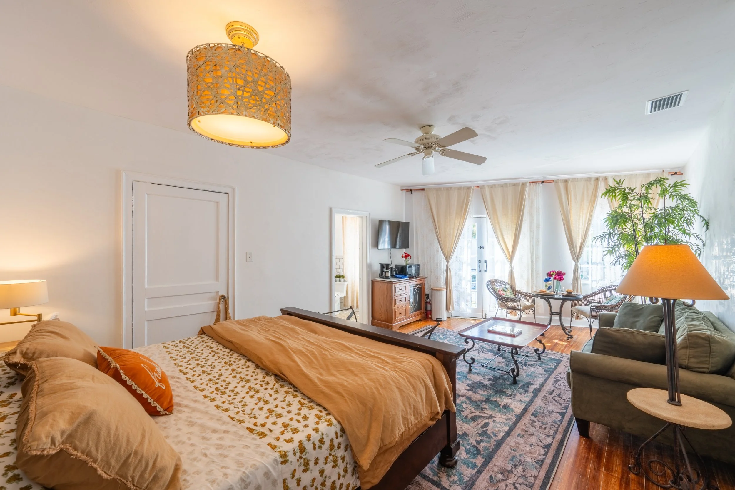 A wide view of a suite with a bed, sofa, coffee table, and lamp
