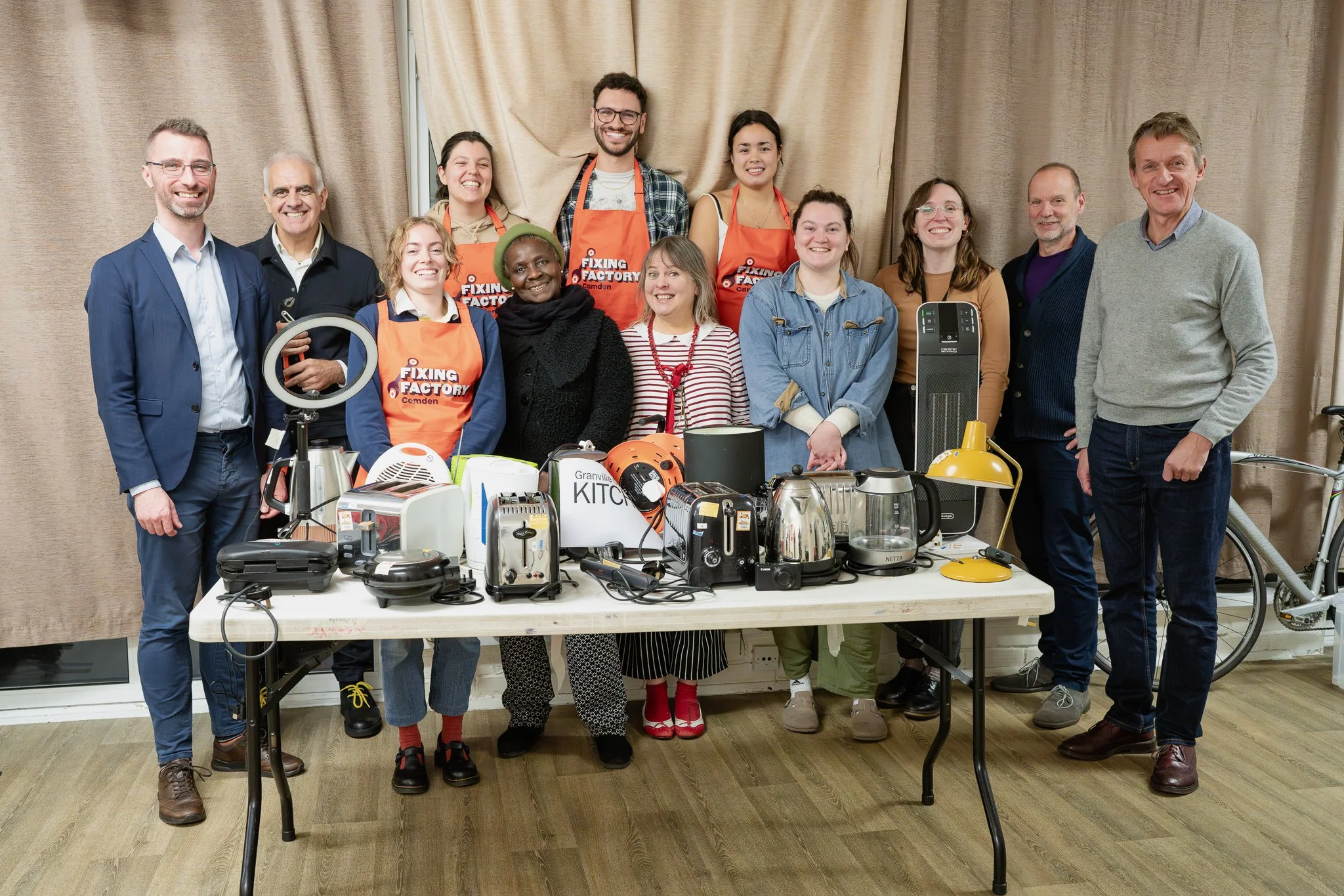 Photo of Fixing Factory team smiling at camera with appliances that they have fixed and saved them going to landfil