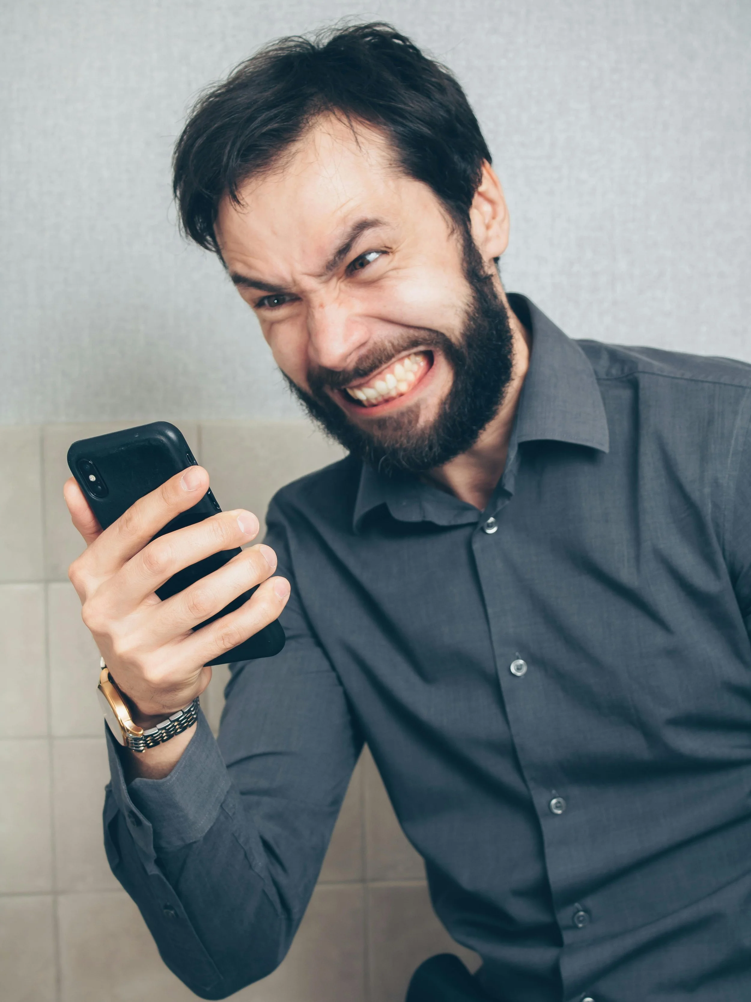 a man with an angry grimace looking at his phone