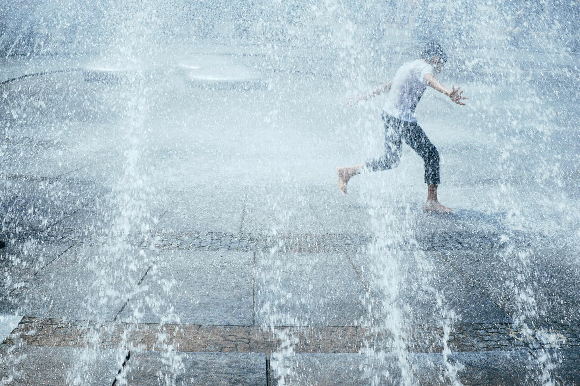 Junge rennt durch Springbrunnen am Karlsplatz in München