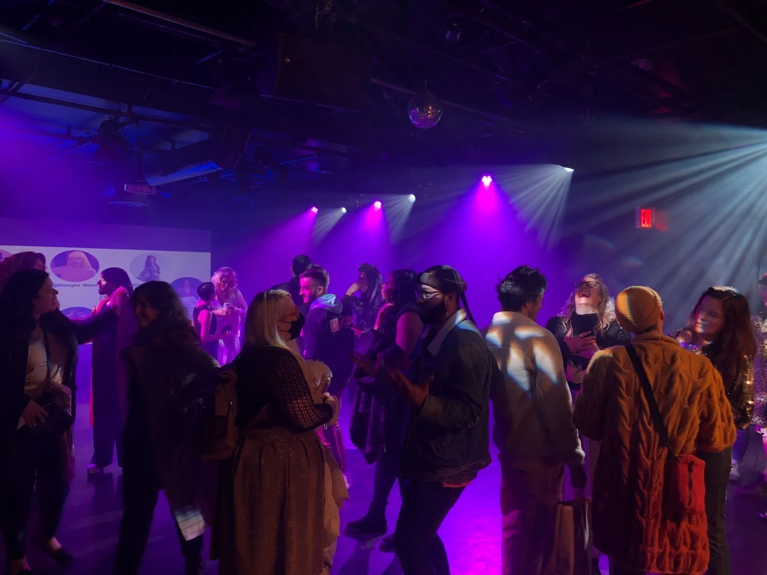 Image of a crowd in the Trisk theater with pink and purple lighting.