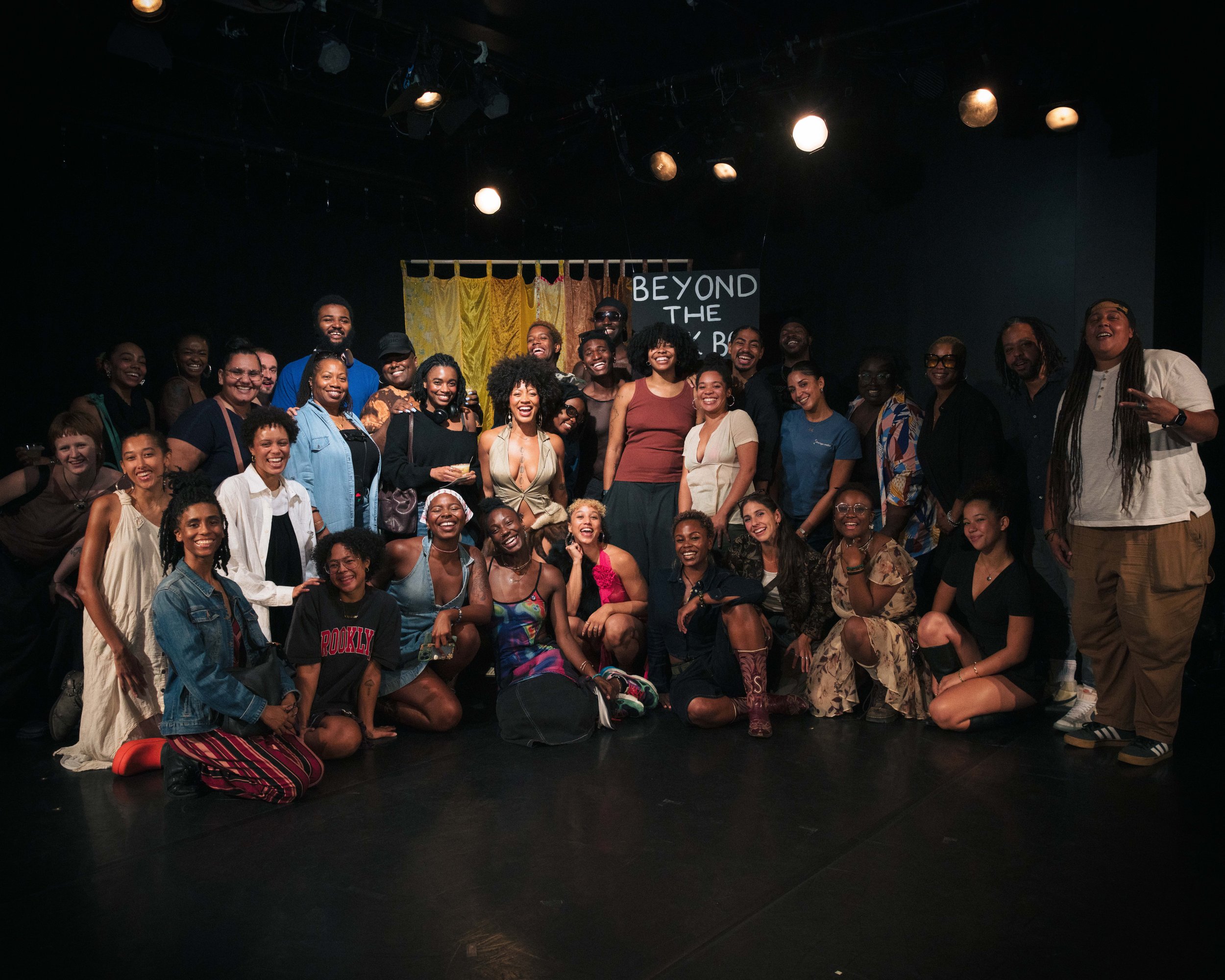A large group of people take a “Family Photo” at The BBB Week’s photobooth, in Triskelion Arts black box theatre.