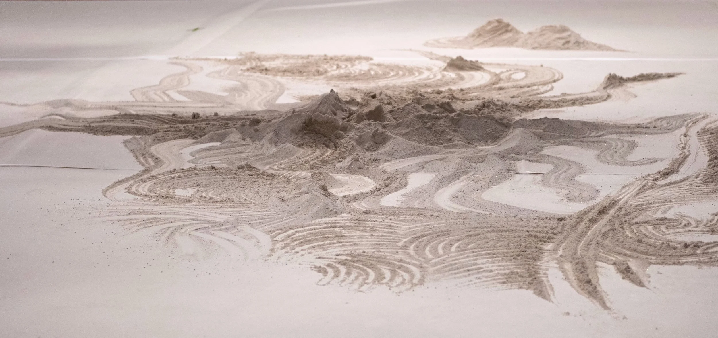 Sand shaped into small dunes on a white floor