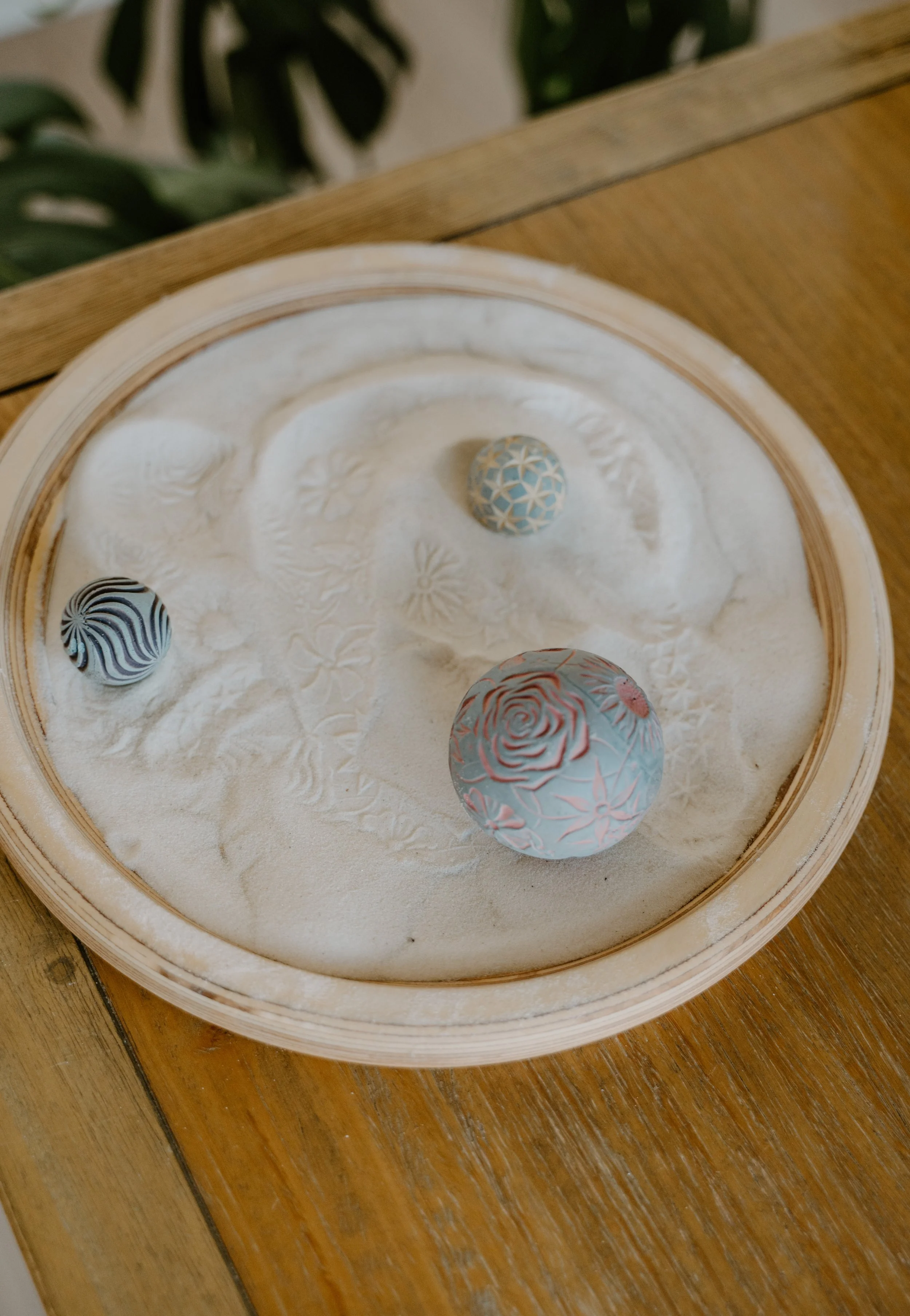 Decorative sand art with three patterned resin spheres in a wooden and glass display case.