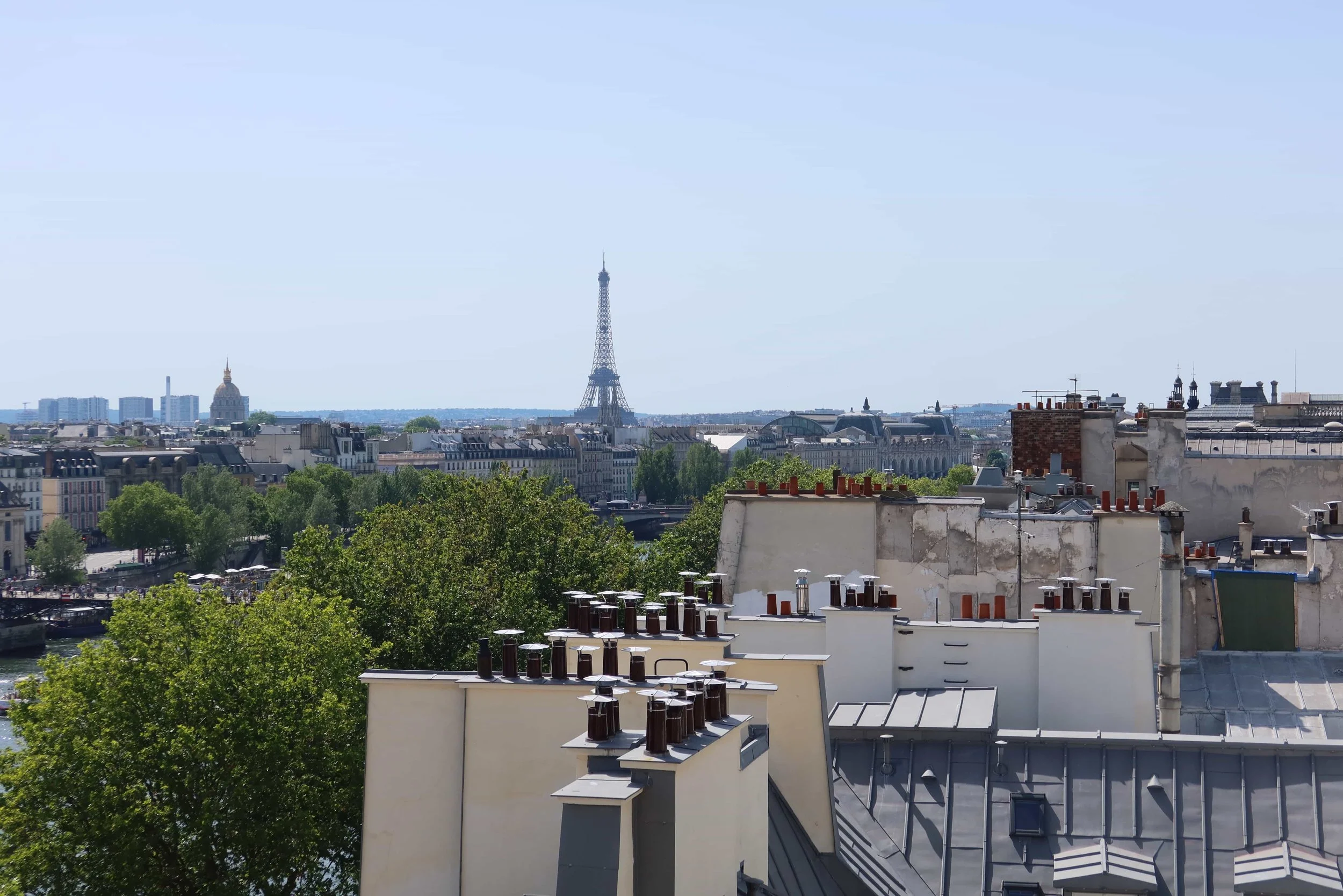 sunny day view of eiffel tower and parisian rooftops