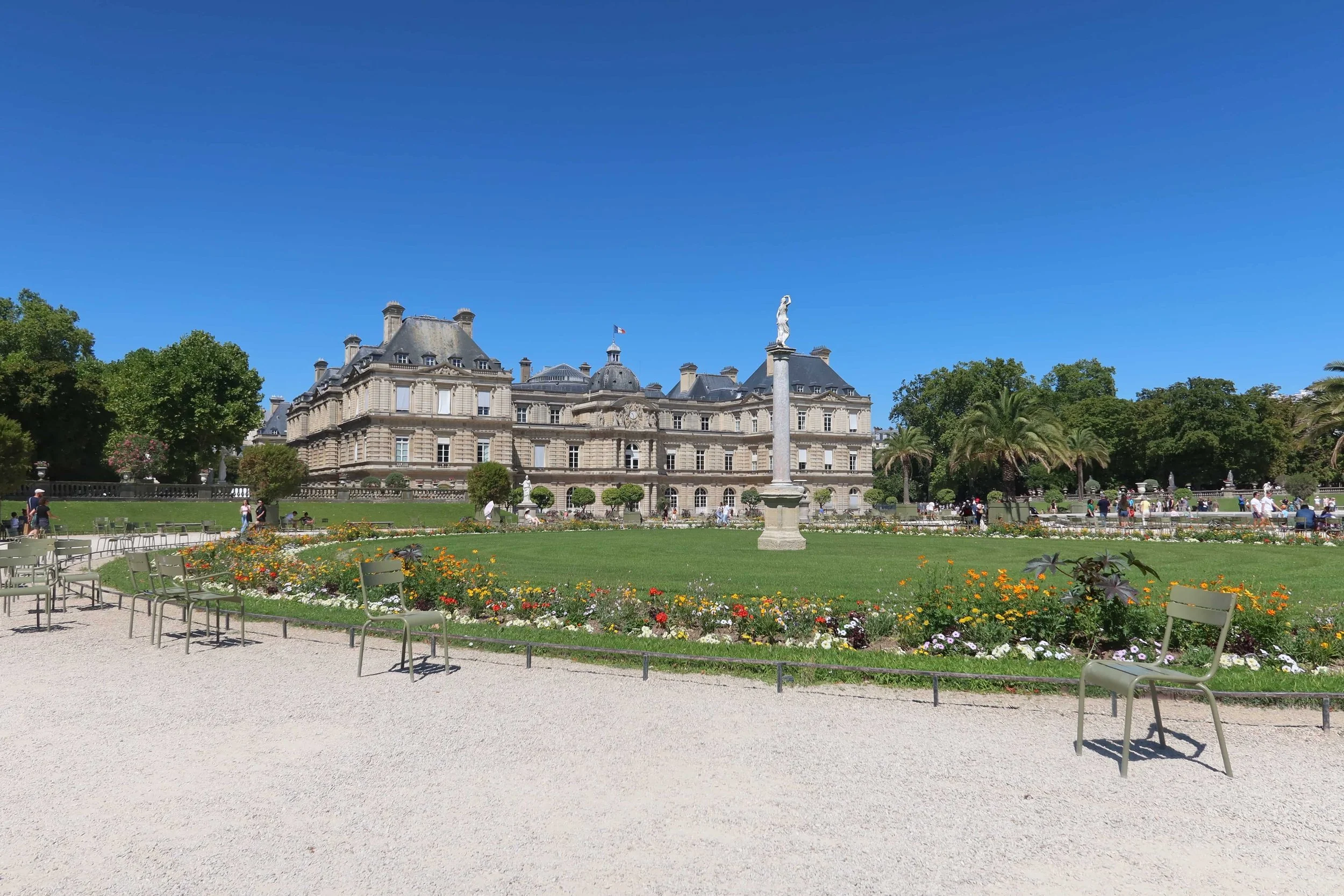 manicured garden with green paris chairs and palace