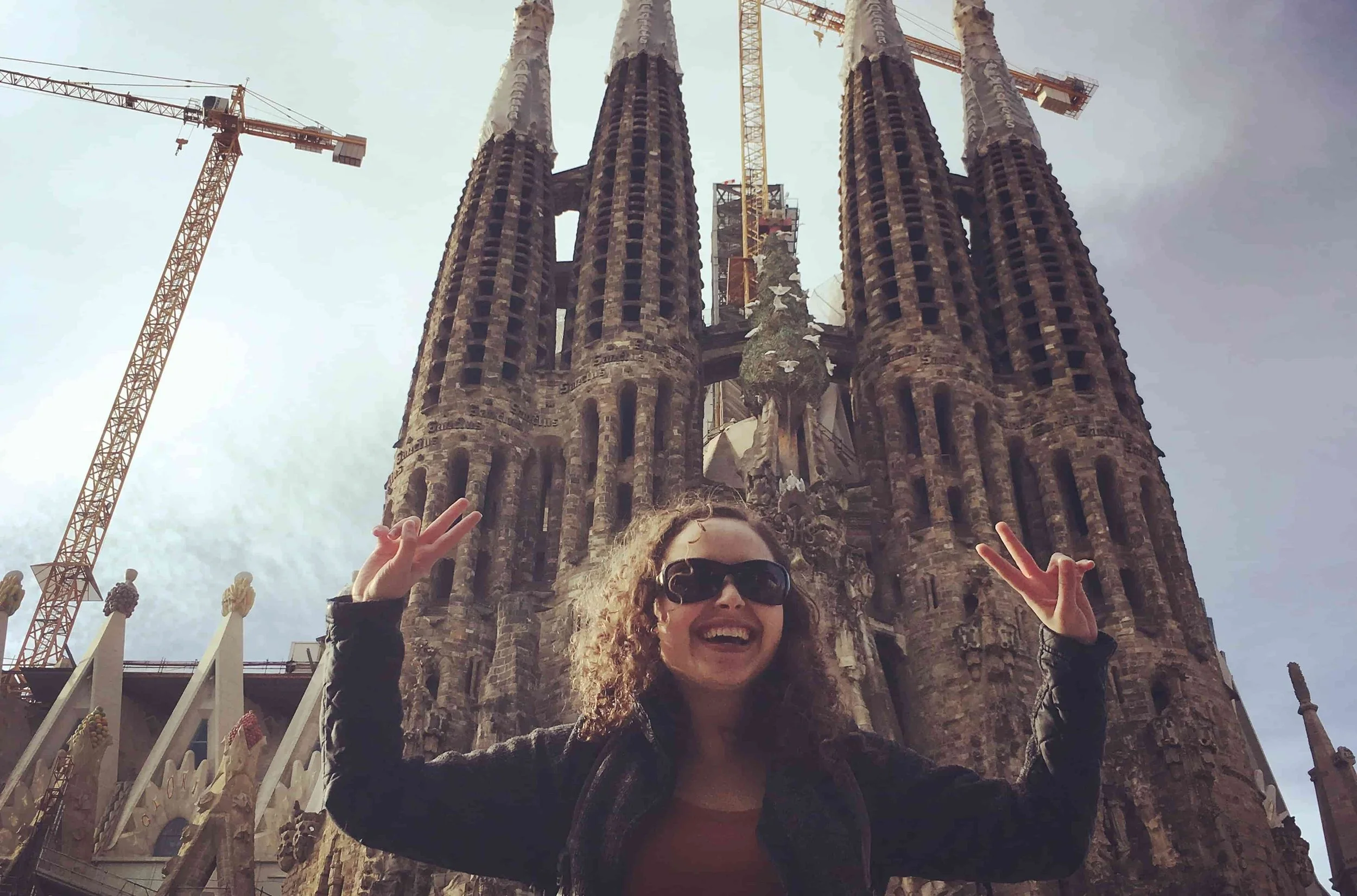 girl holding peace signs standing in front of la sagrada familia