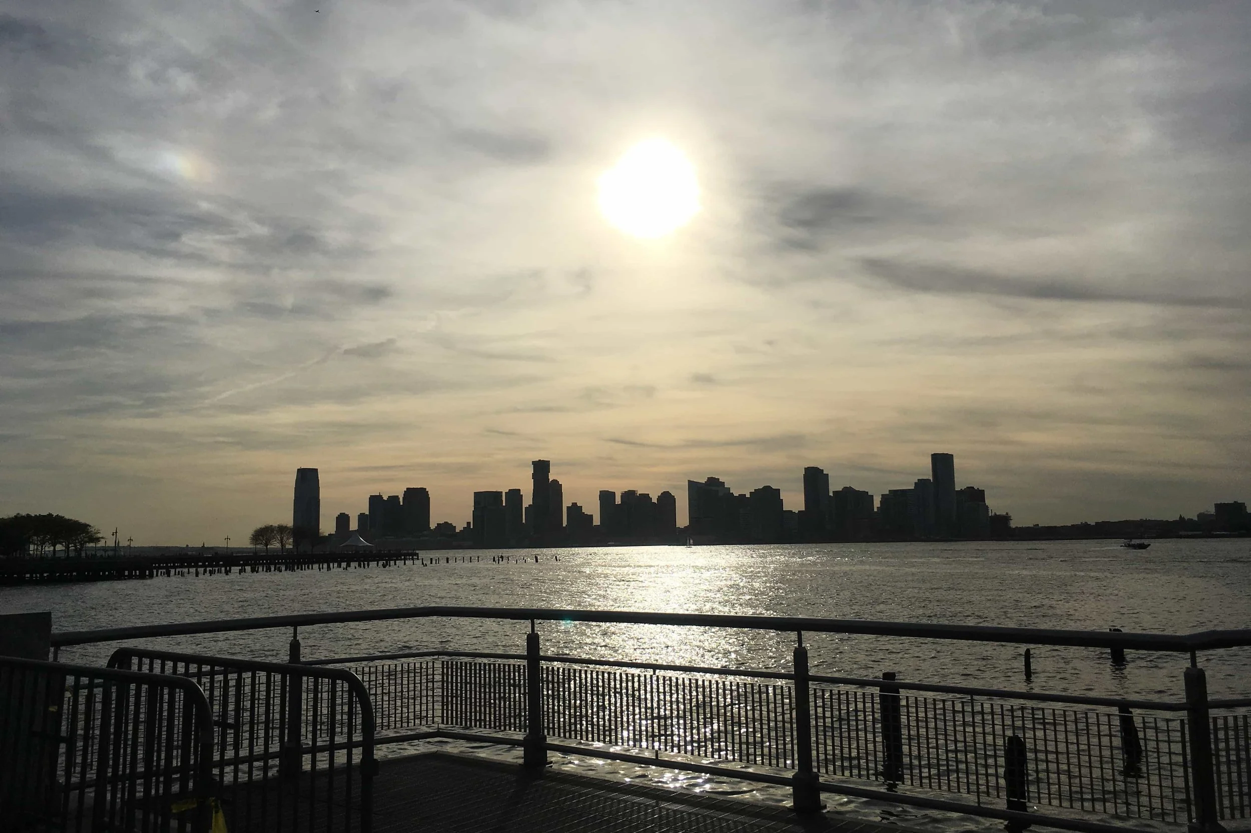 sparkling water hudson river with buildings and gold sunset in the distance