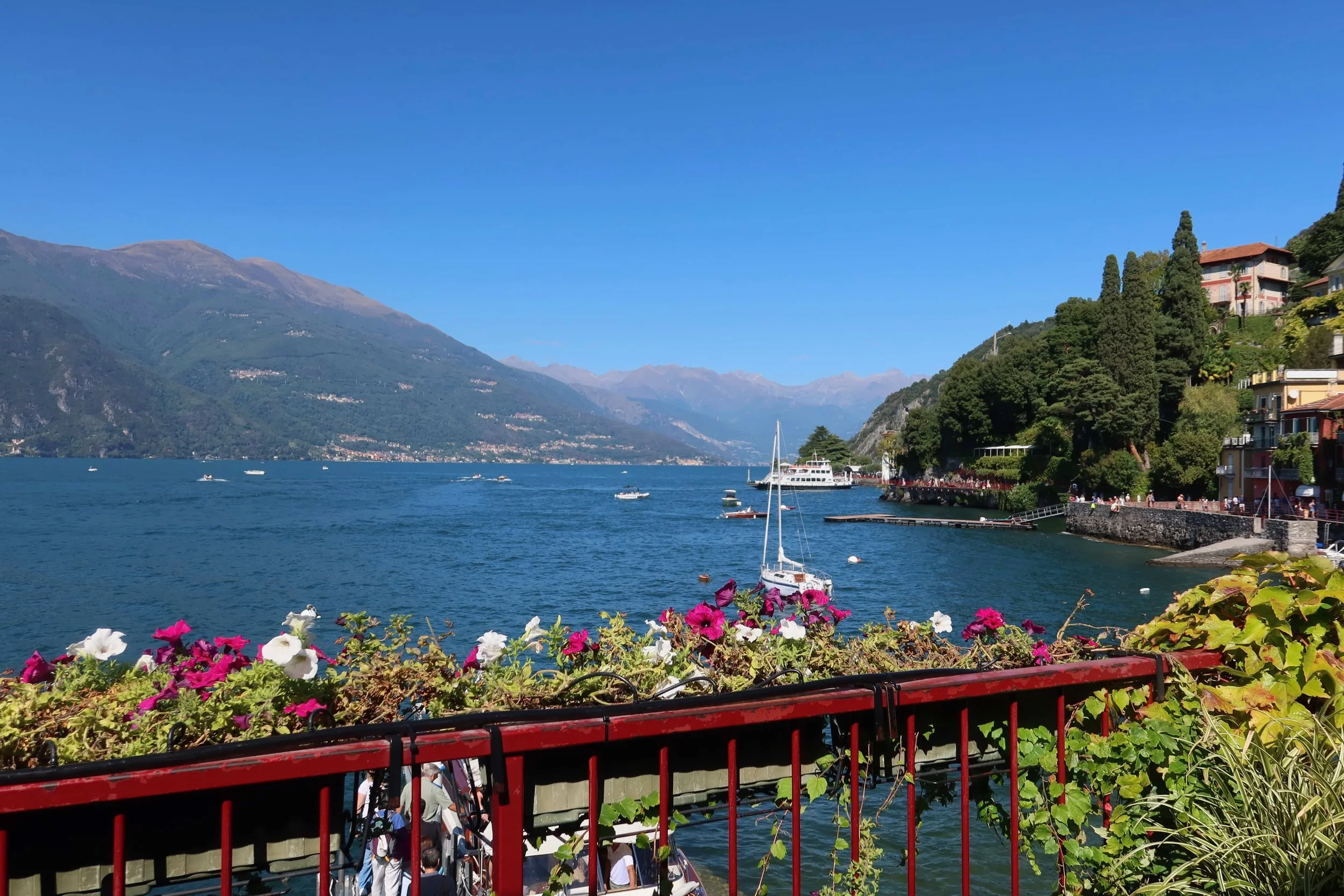 red banister with boats flowers and mountains in the distance