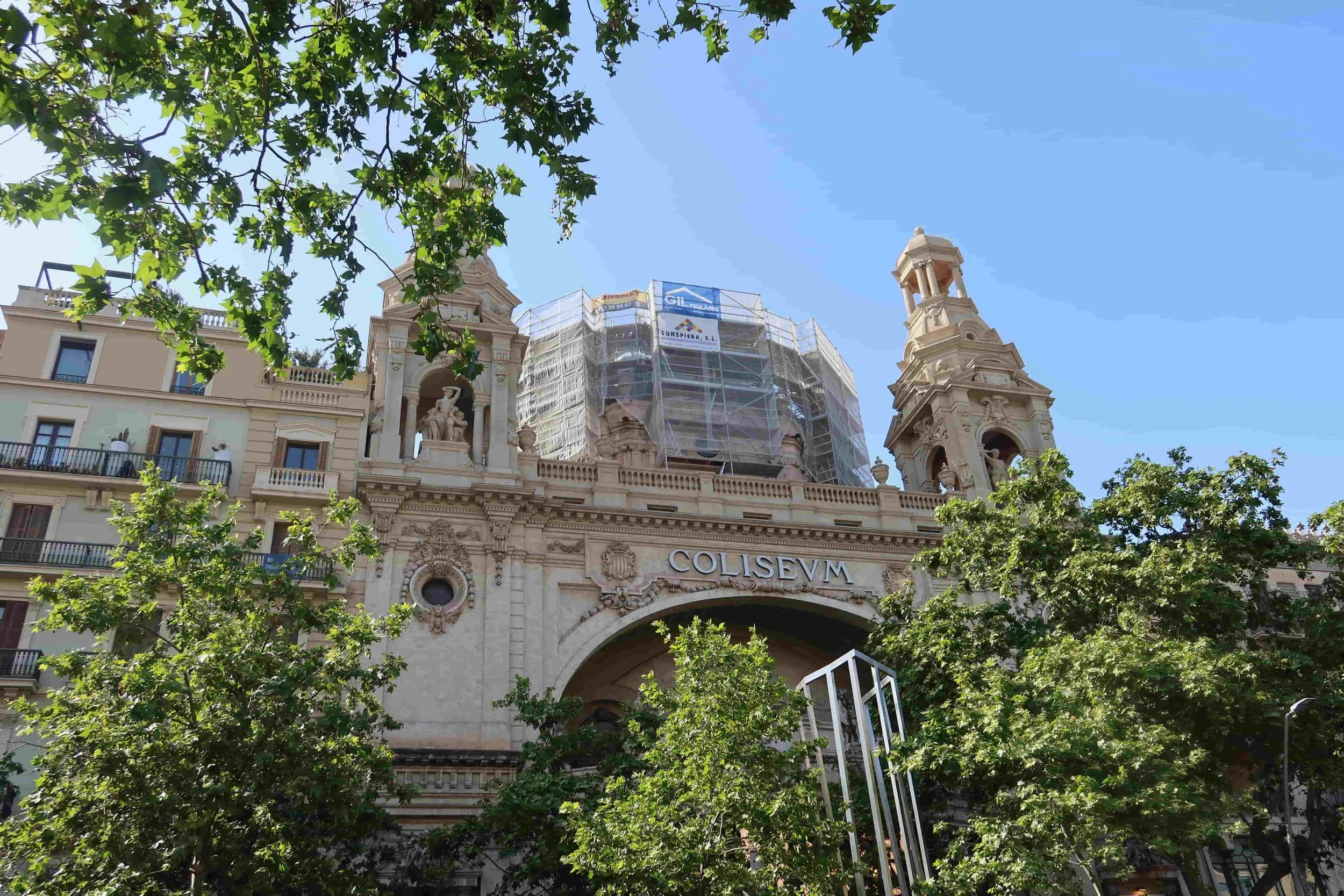 white palace on busy street in barcelona surrounded by leafy green trees