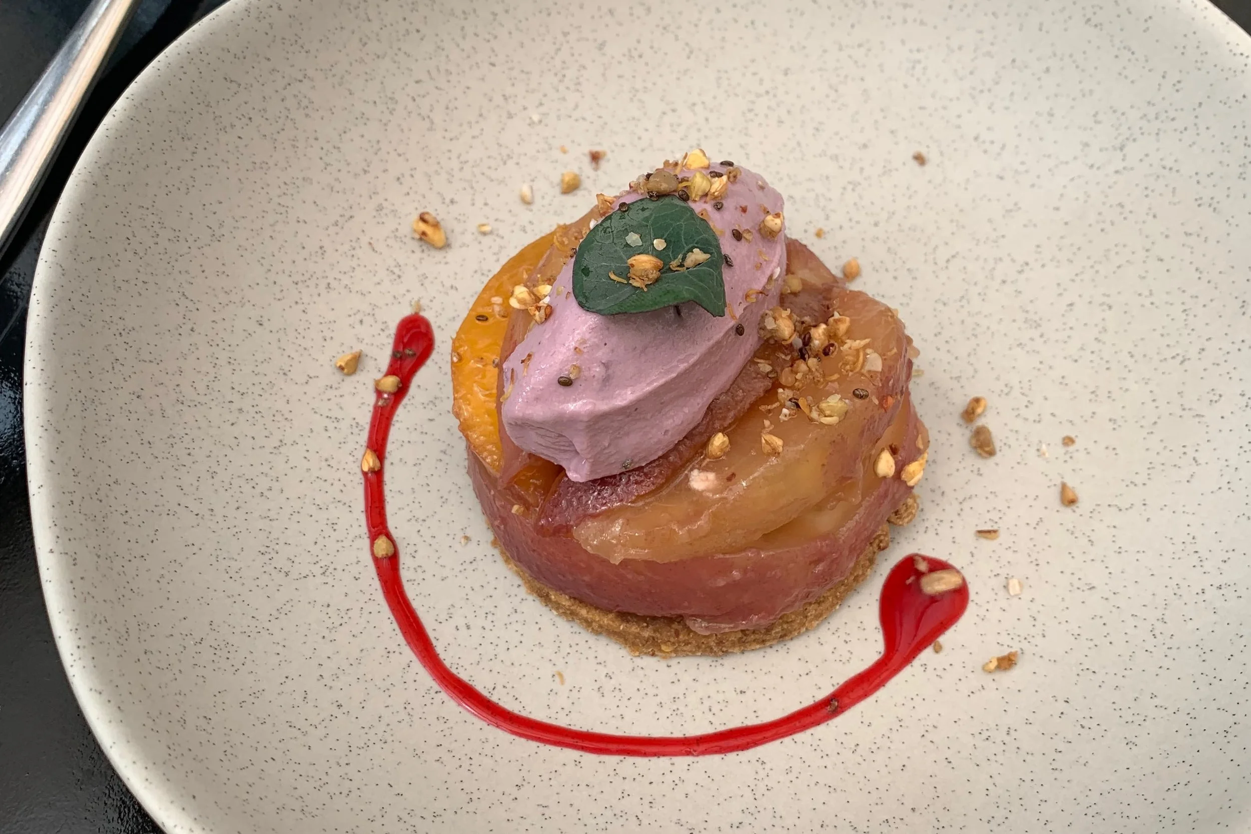 raw peach tart with purple ice cream and mint leaf