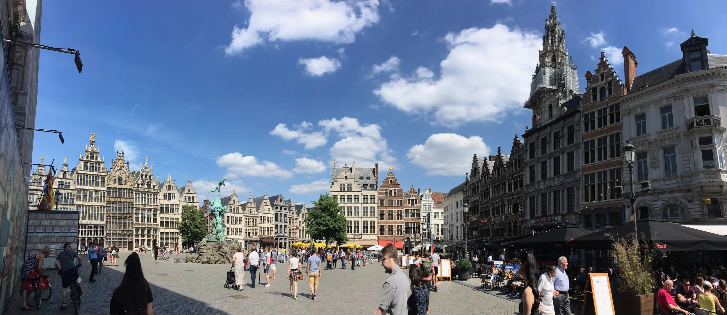 main square in antwerp with belgian architecture and people and cafes blue skies