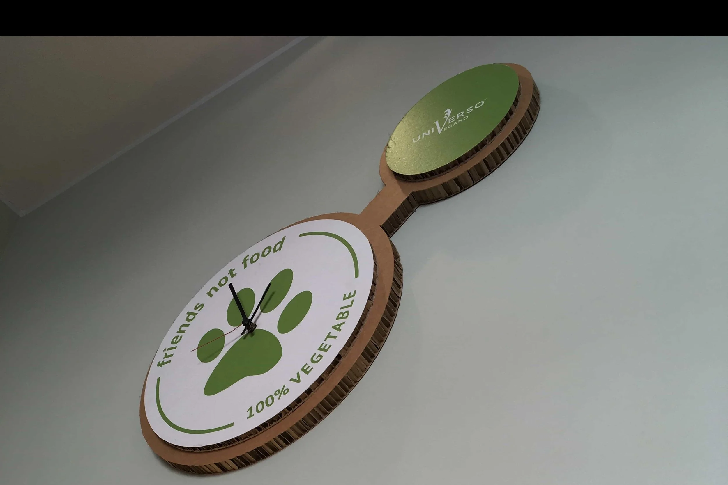 green paw print clock on white wall