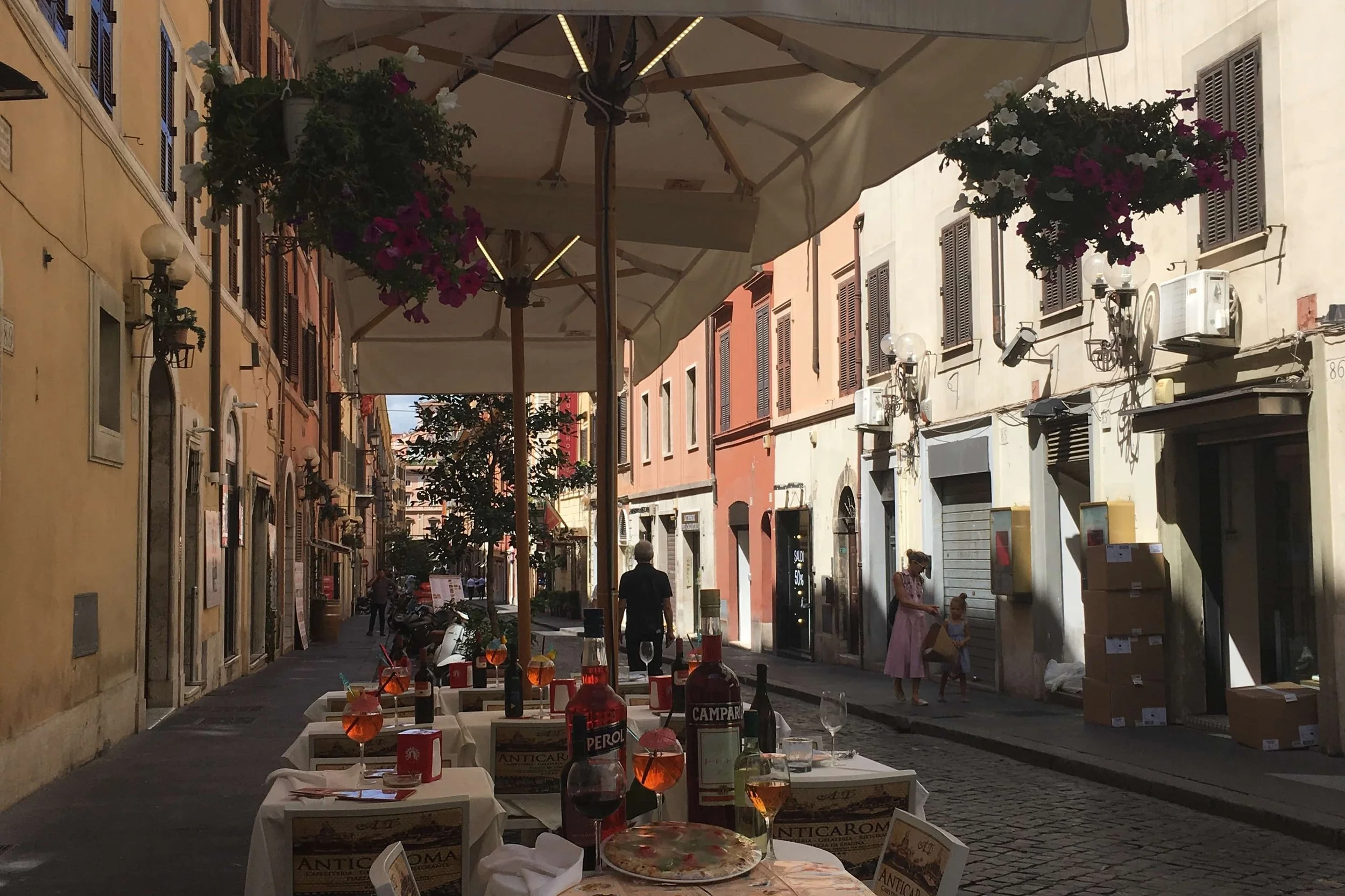 wine and aperol spritz on white cloth tables on quiet rome street
