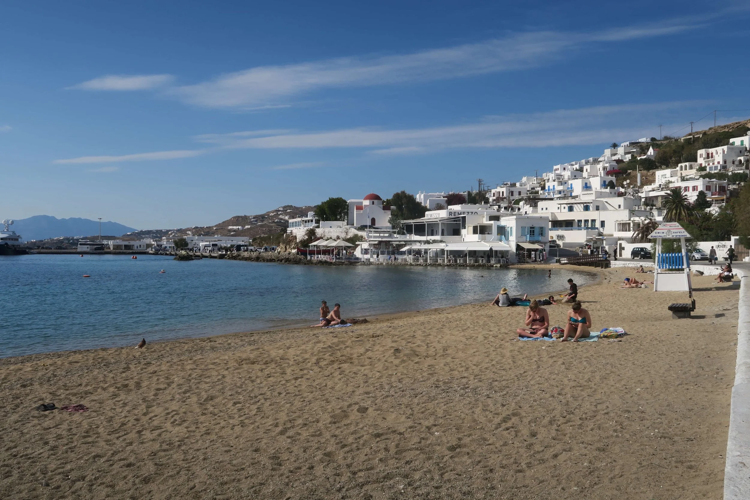quiet beach with water and mountains and white houses in background