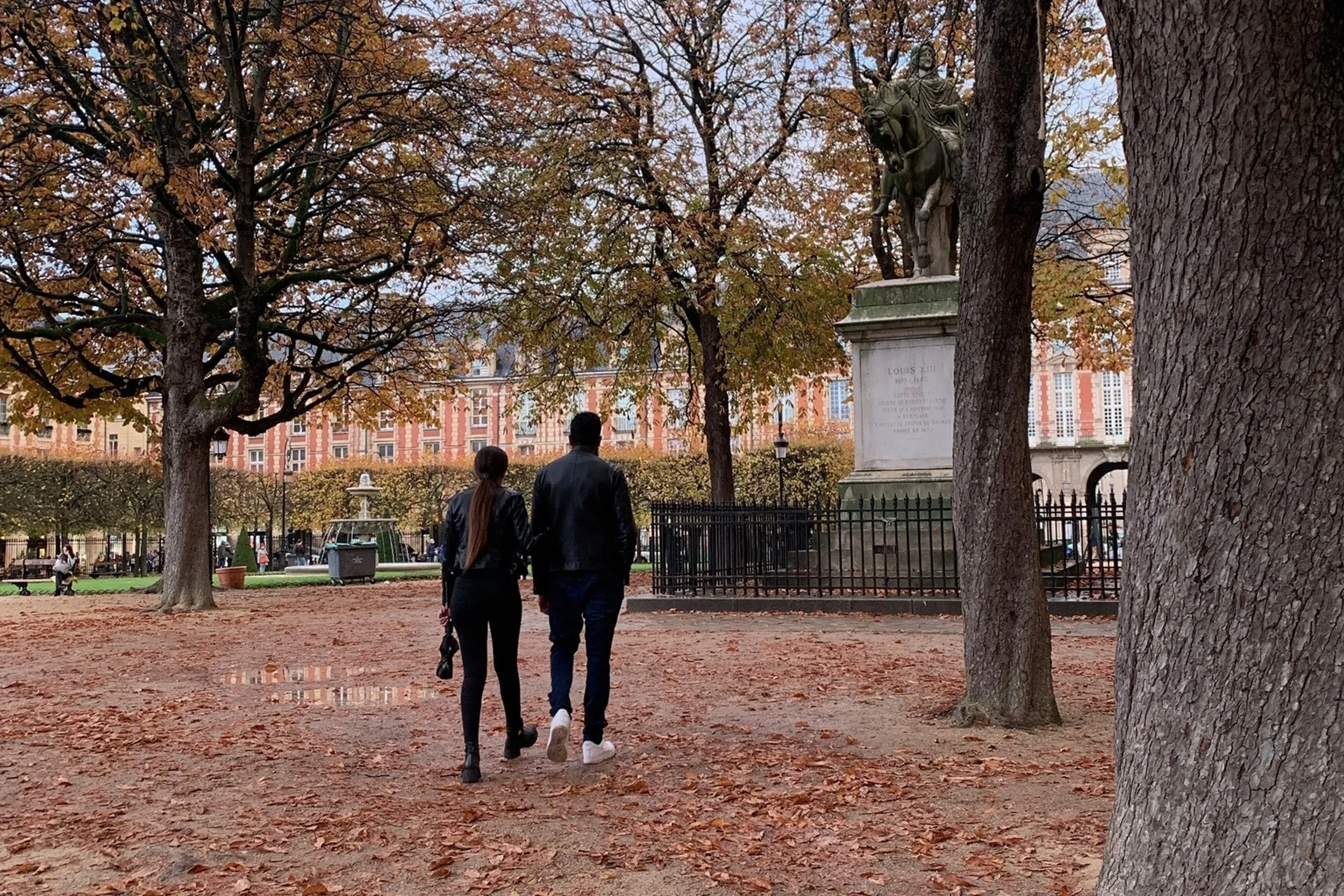 couple walking through park in paris in autumn foliage
