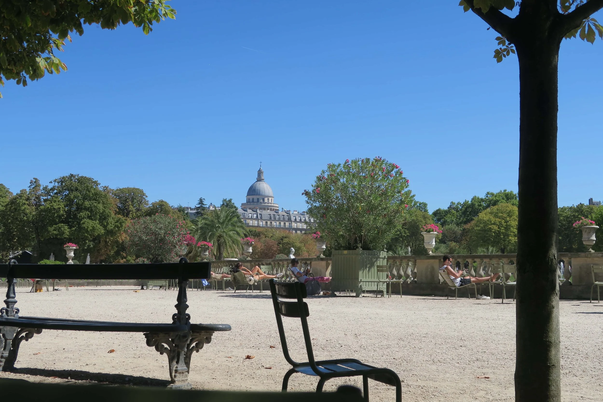 strong sun blue skies in paris park pantheon in distance