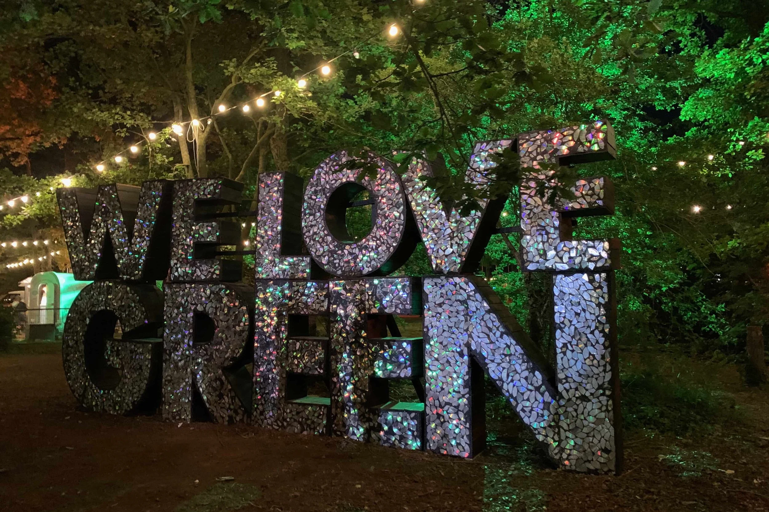 we love green silver sign at night with green trees behind it