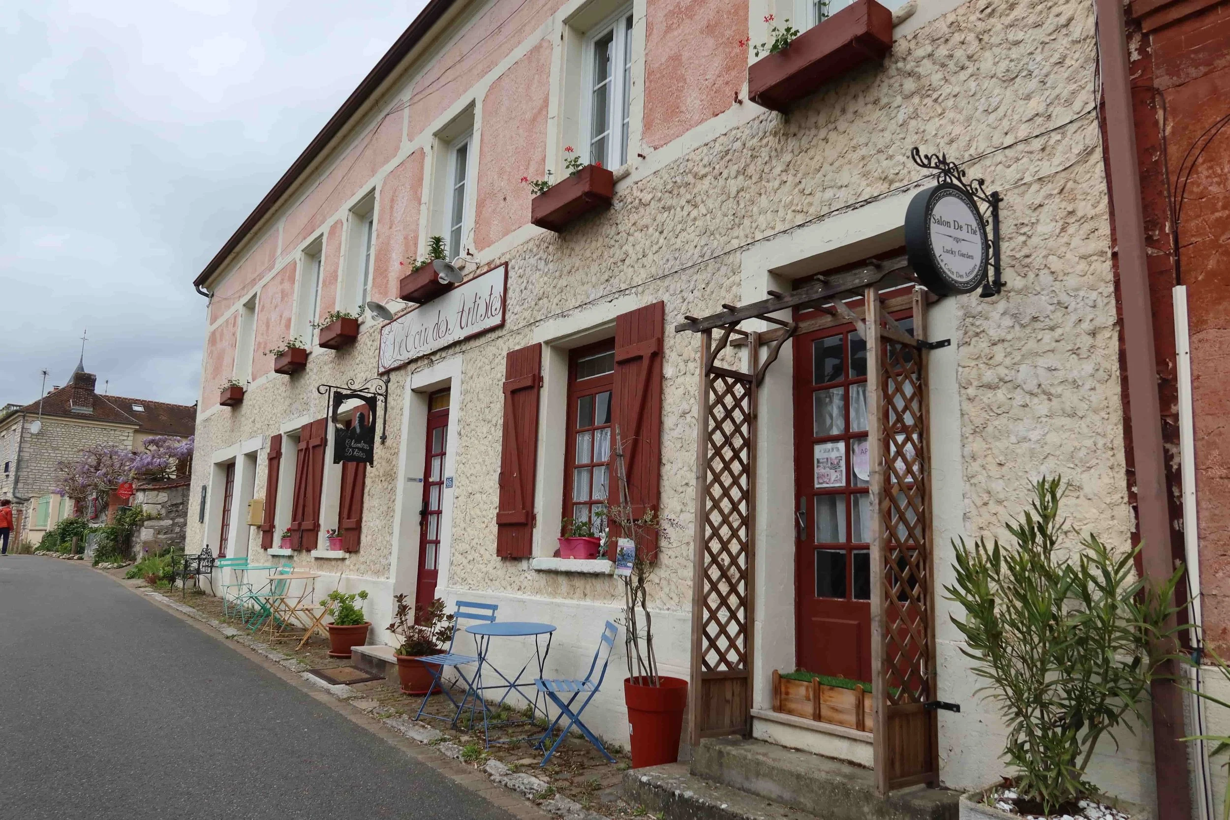 rue claude monet blue chairs and red painted windows old cafe building giverny