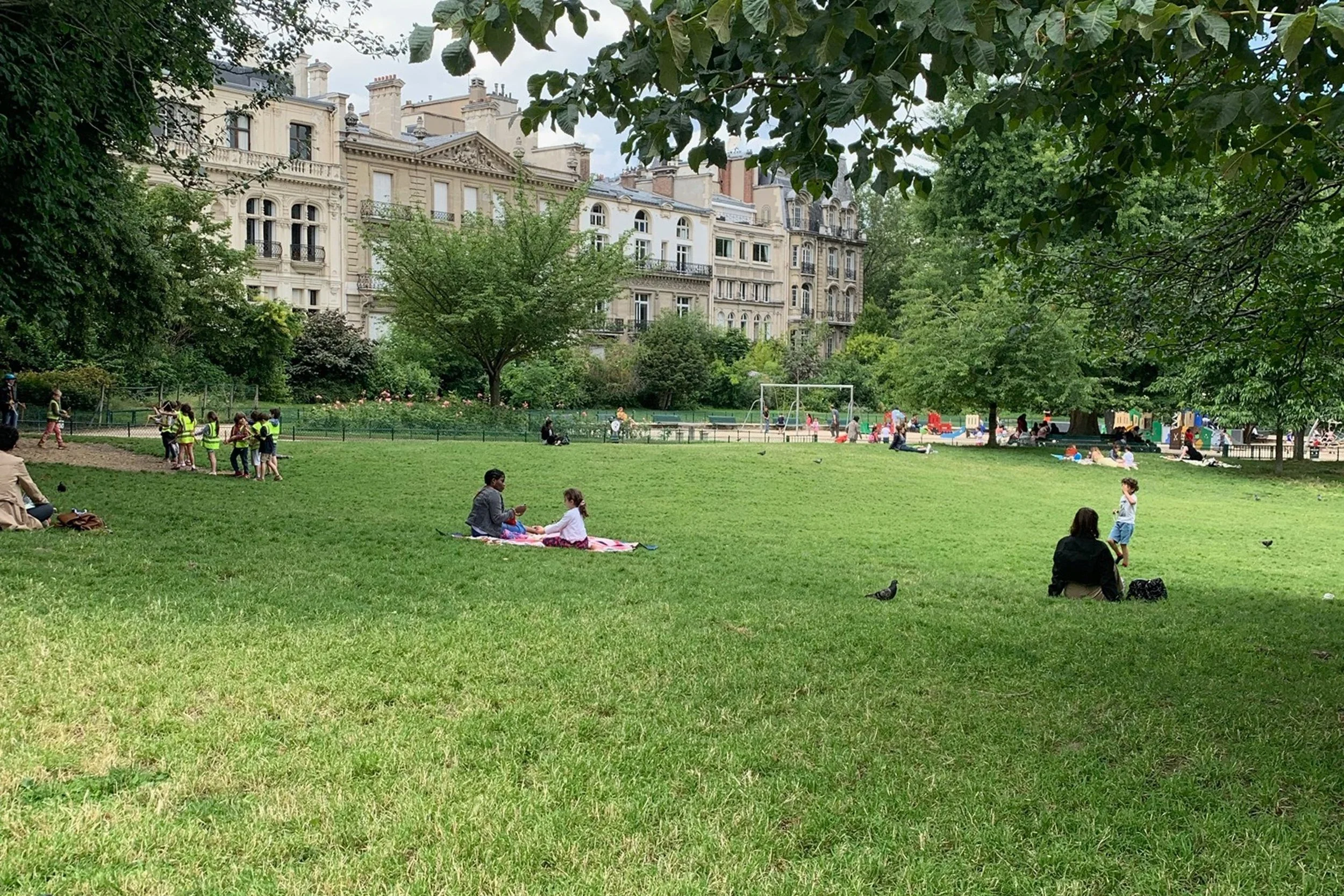 green park with famimlies and kids outside playground
