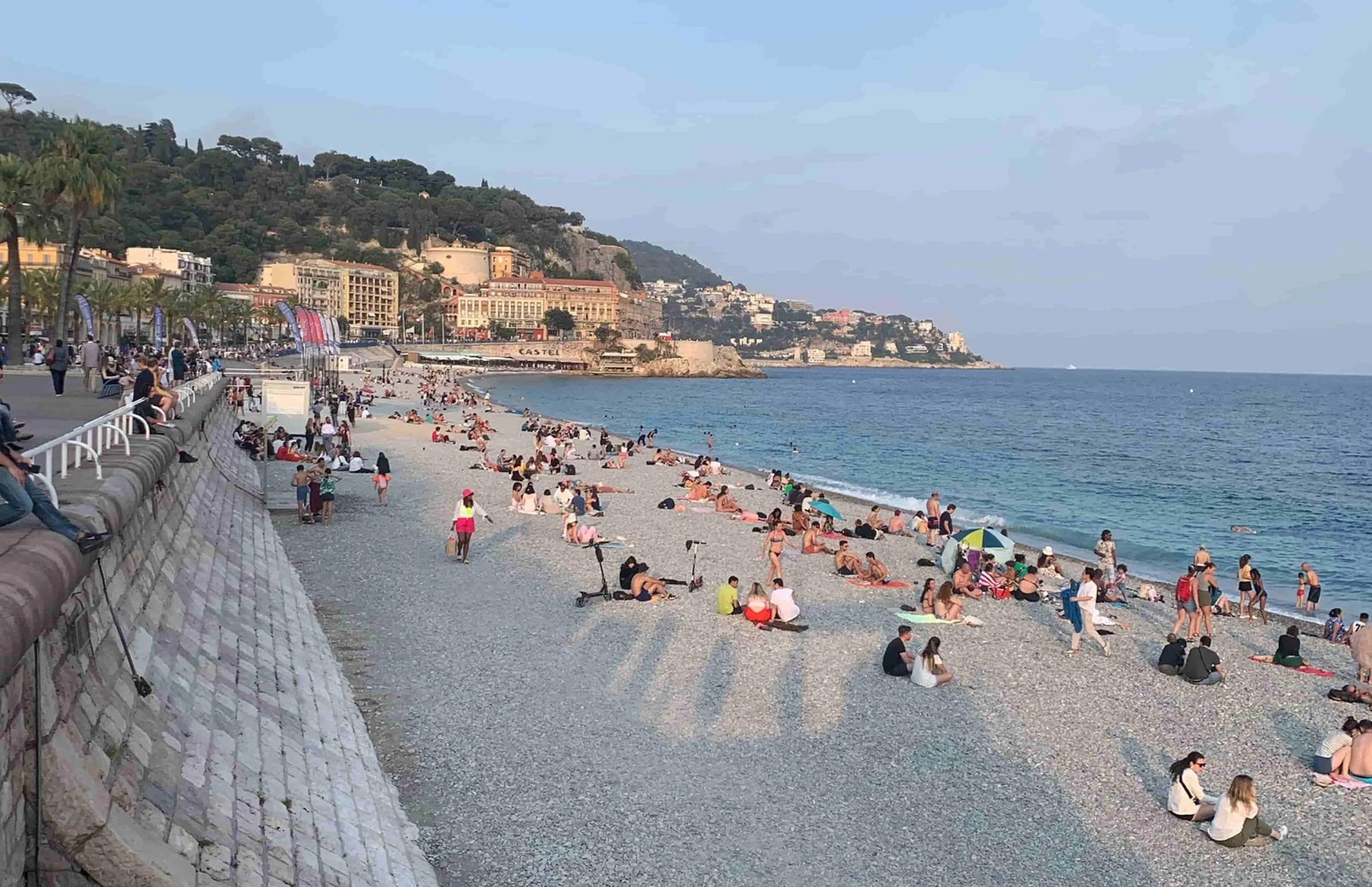 people on beach busy with little cliffs and pebbles grey for sand