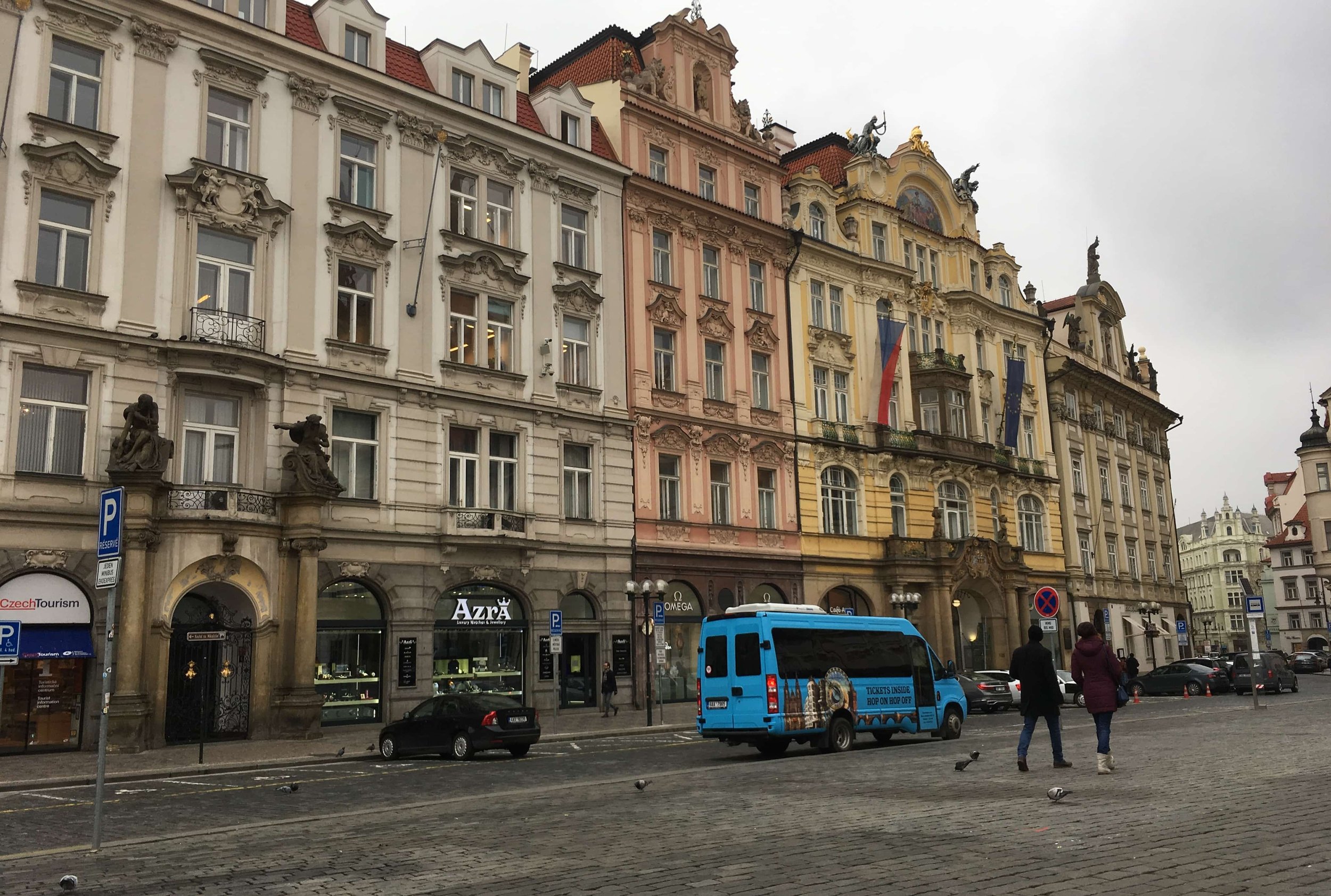 colorful streets of prague with blue car and people on street