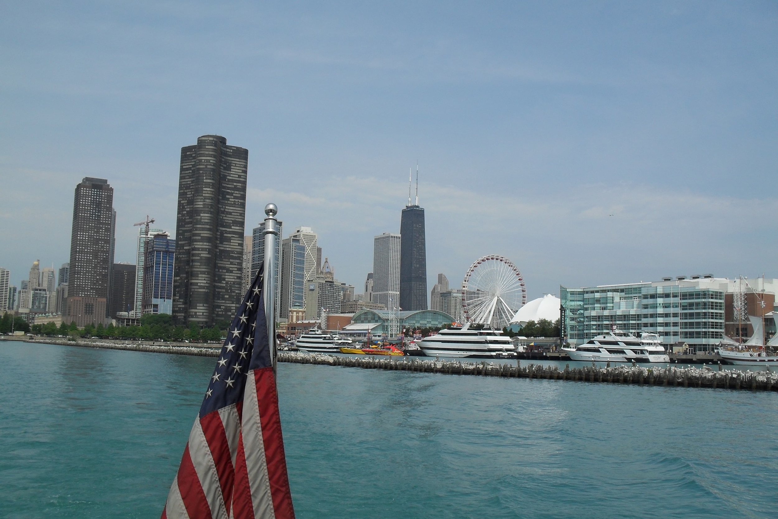 chicago skyline from lake ferris wheel and american flag on boat
