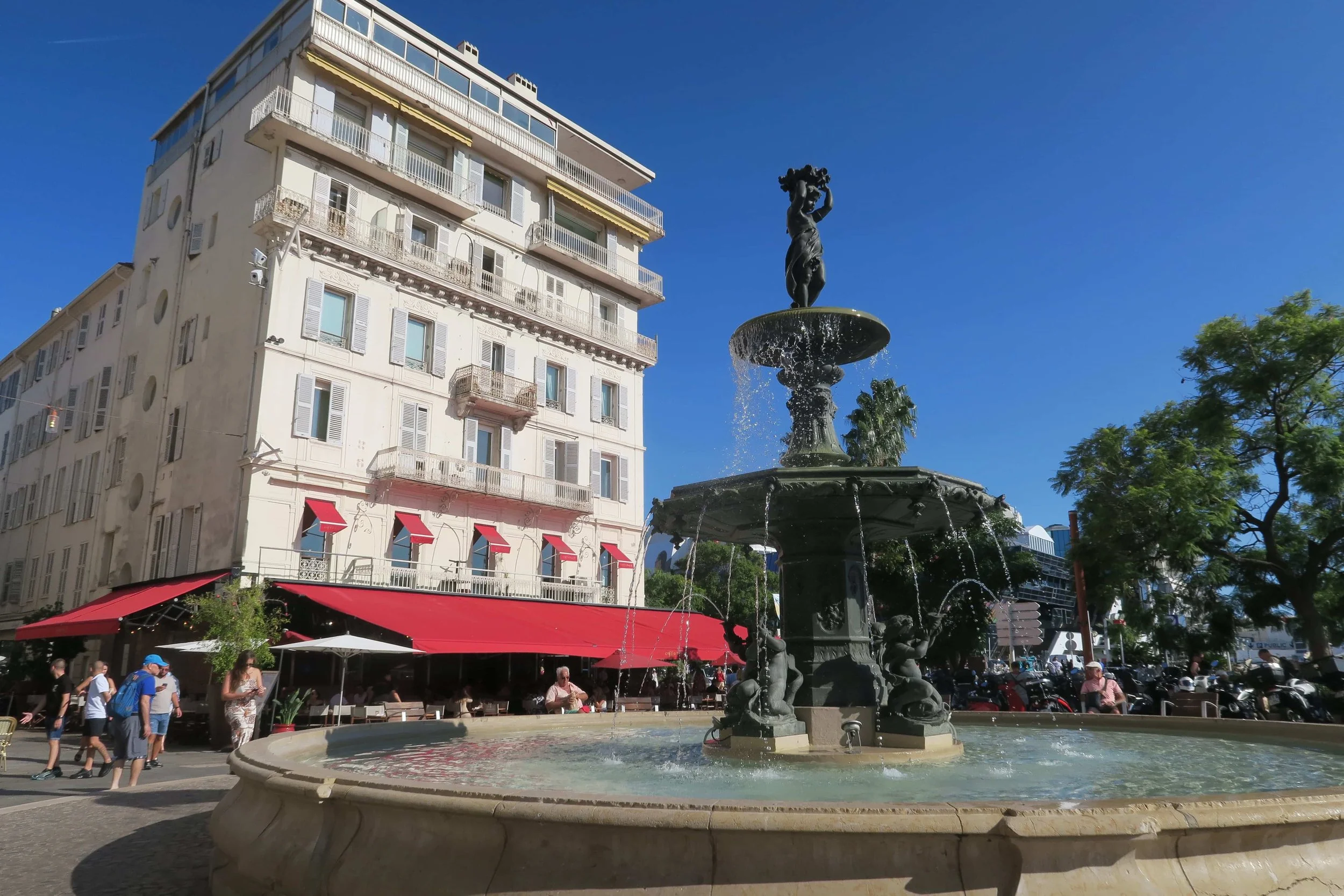 cannes fountain with white building and red awning