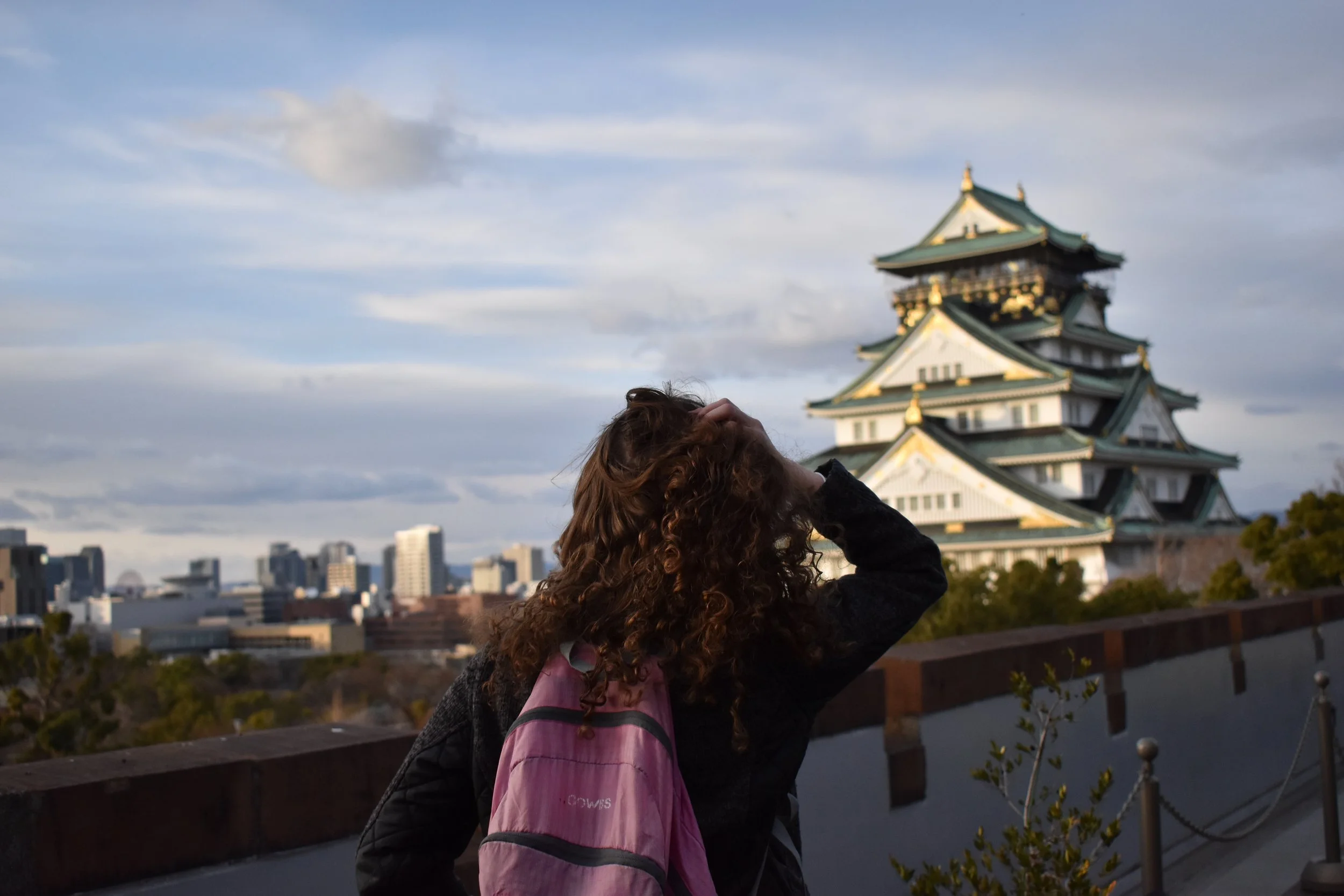 pink foldable day pack while seeing temples in japan cloudy day