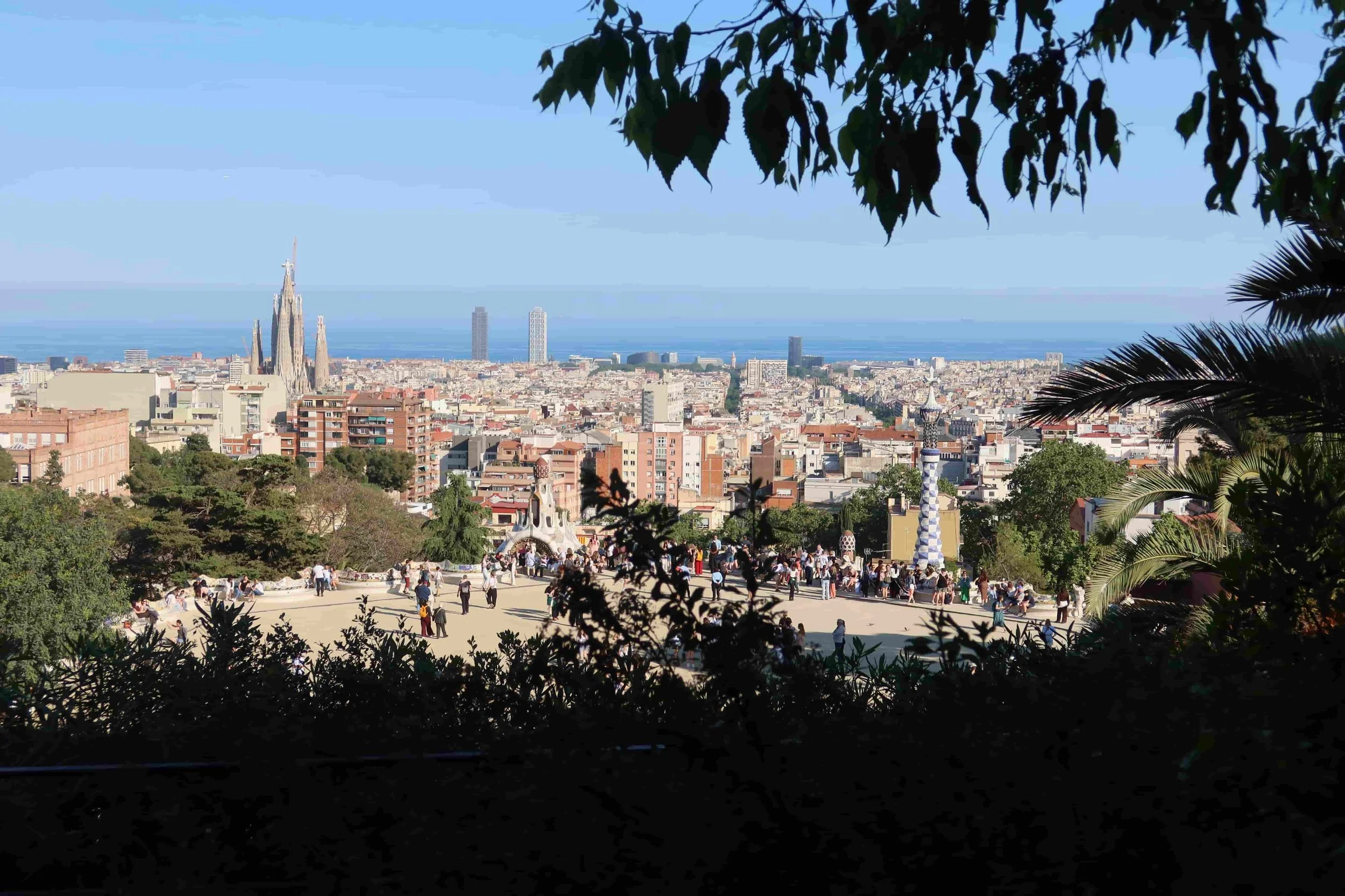 sunny view of park guell with ocean and la sagrada familia