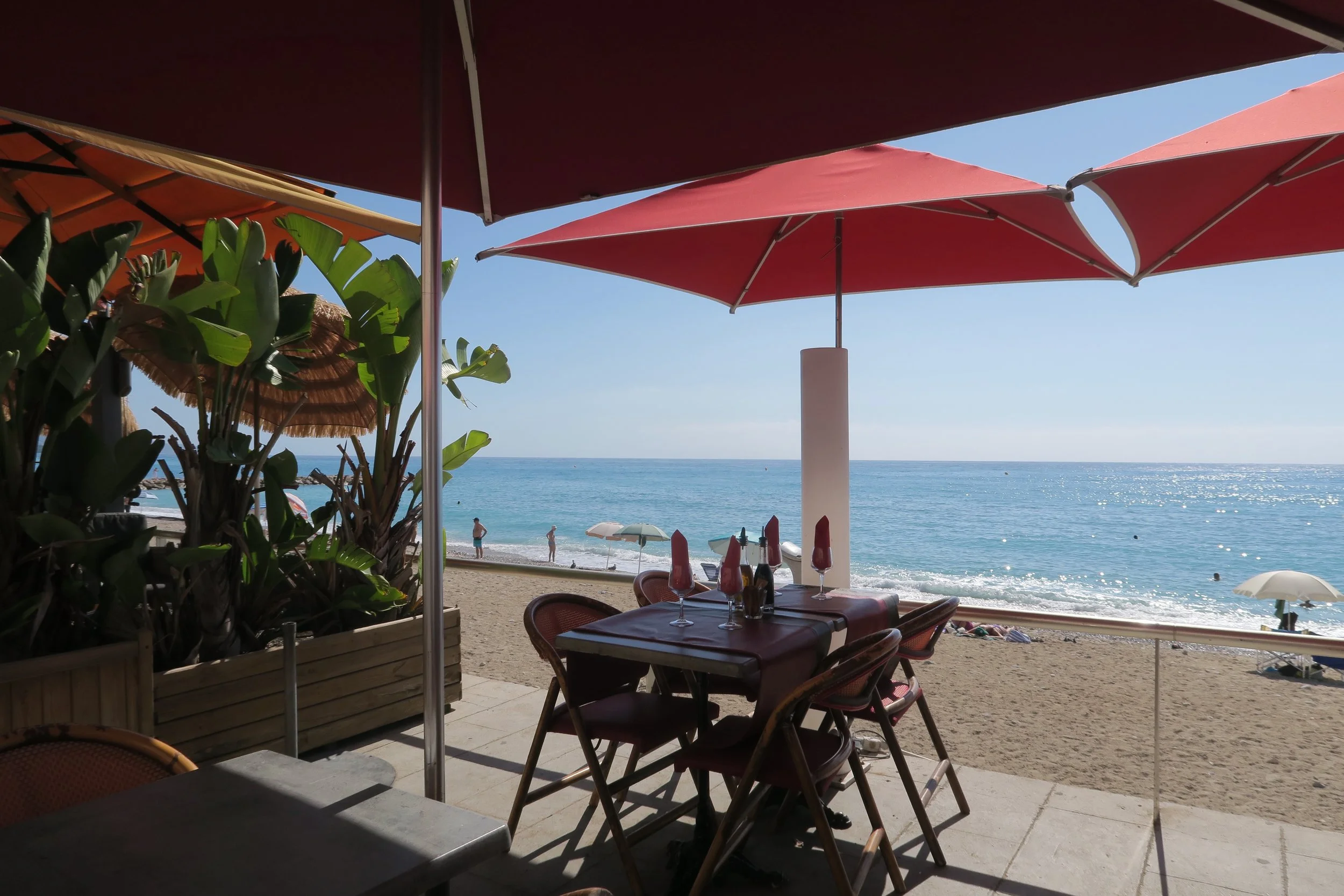 red umbrella and lunch tables near beach in menton