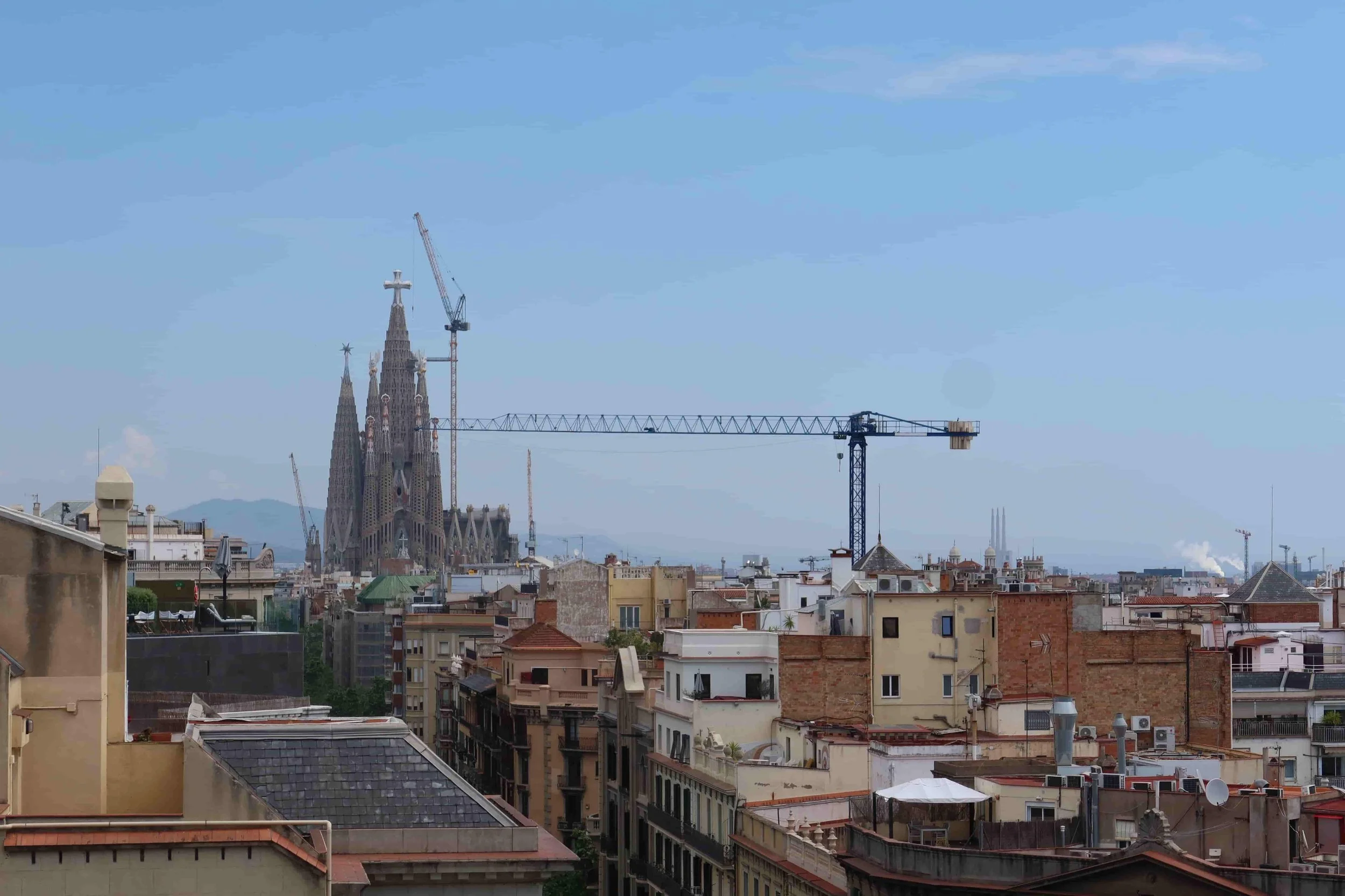 view of sagrada familia from casa mila with barcelona rooftops