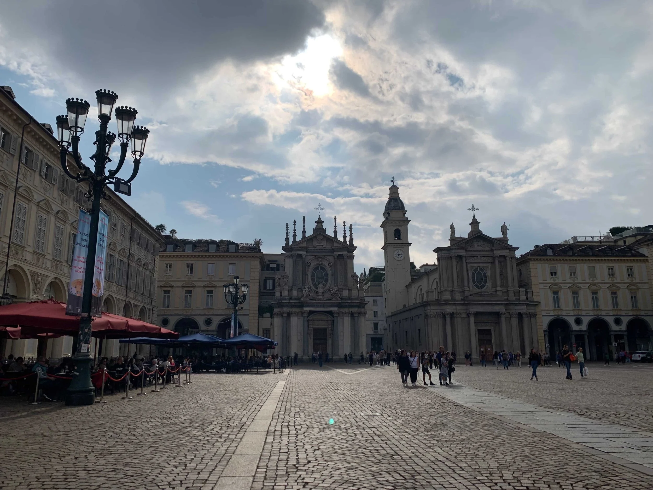 plaza in italy with clock tower and cafes