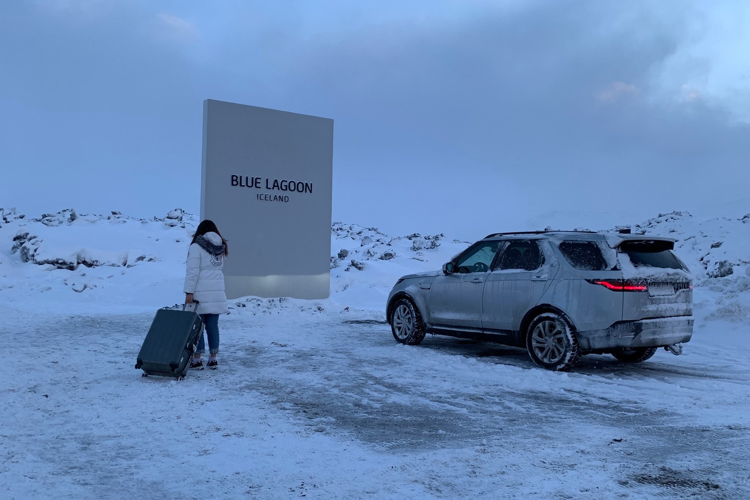 blue lagoon parking lot suv and girl with suitcase